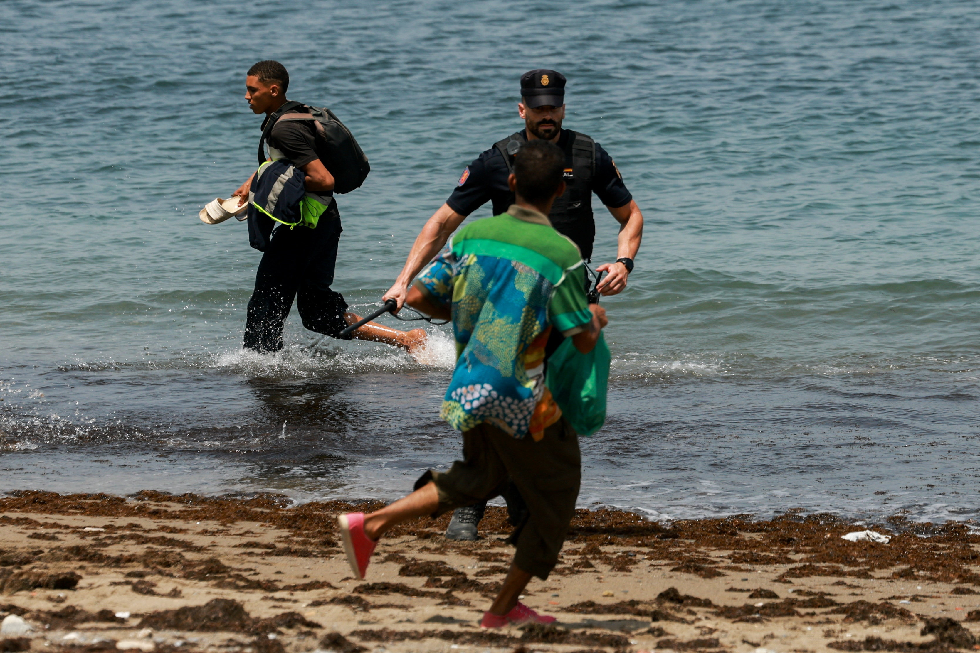 Migrants try to make their way past Spanish police officers, following recent mass crossings of migrants on foot and by sea from Morocco into Spanish territory, in Ceuta, Spain, August 1, 2026. REUTERS/Violeta Santos Moura