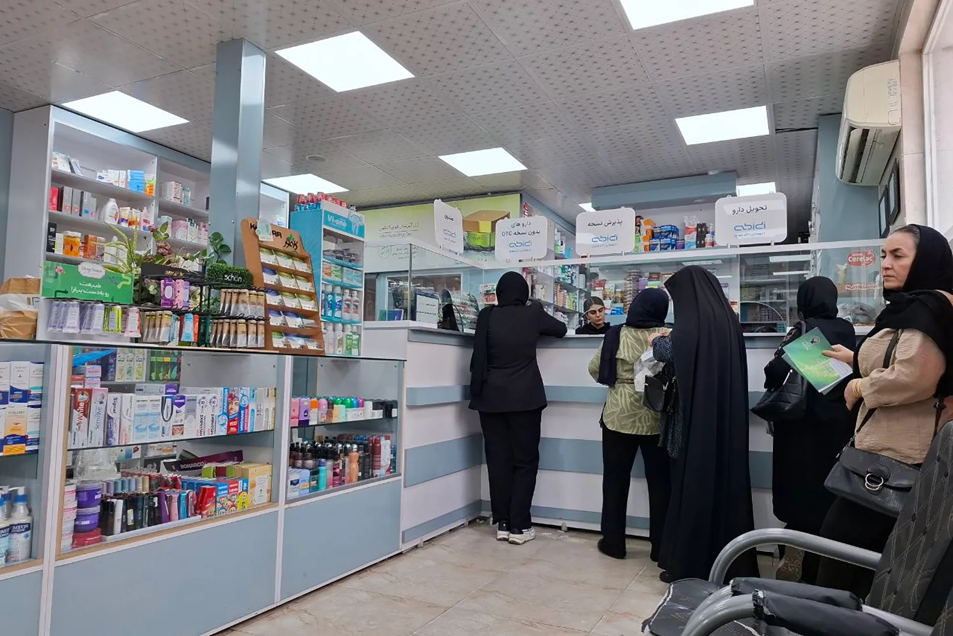 Women queue at a pharmacy in Tehran [Al Jazeera]