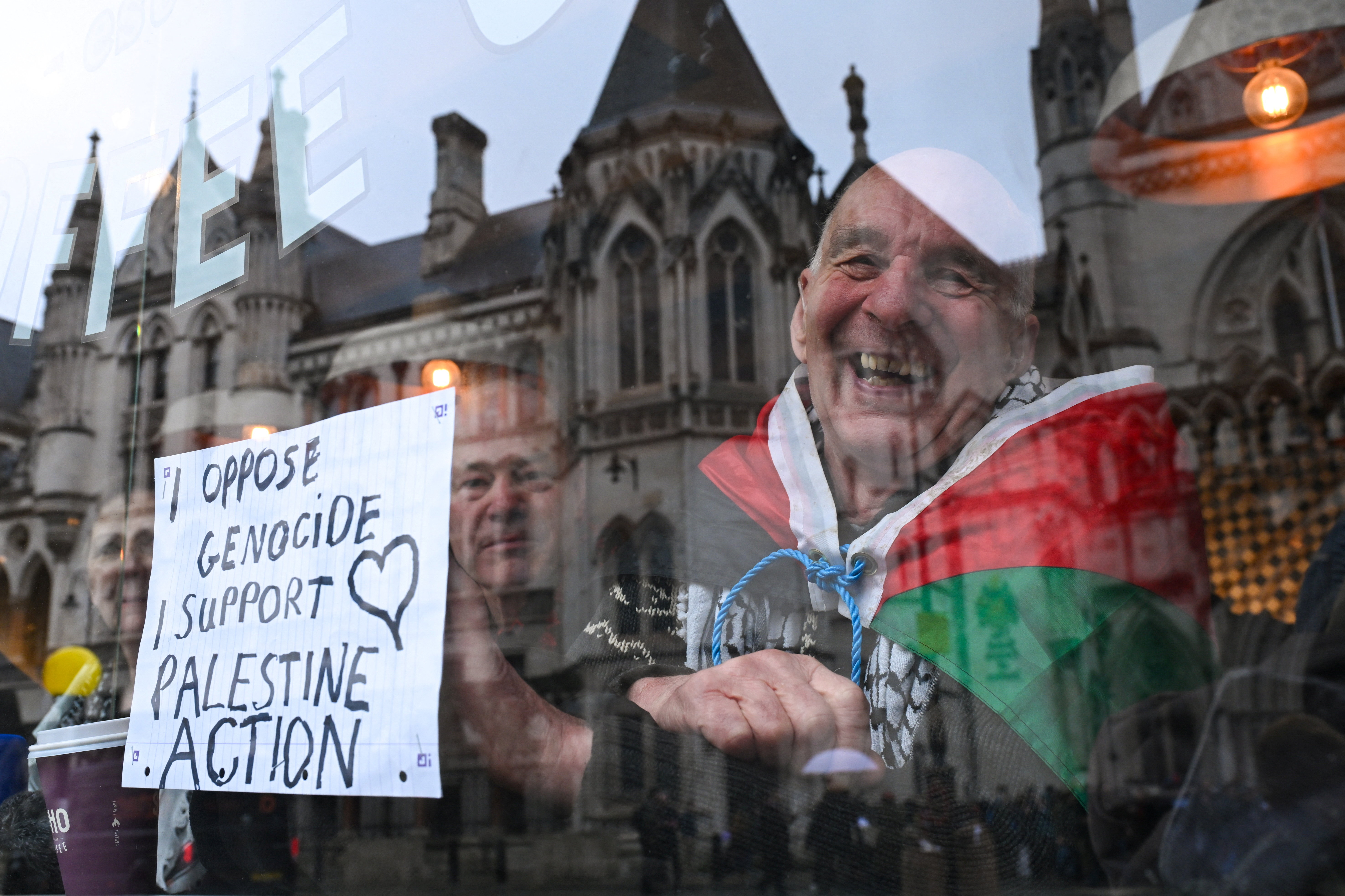 A man with a Palestinian flag draped around his shoulders reacts inside a cafe
