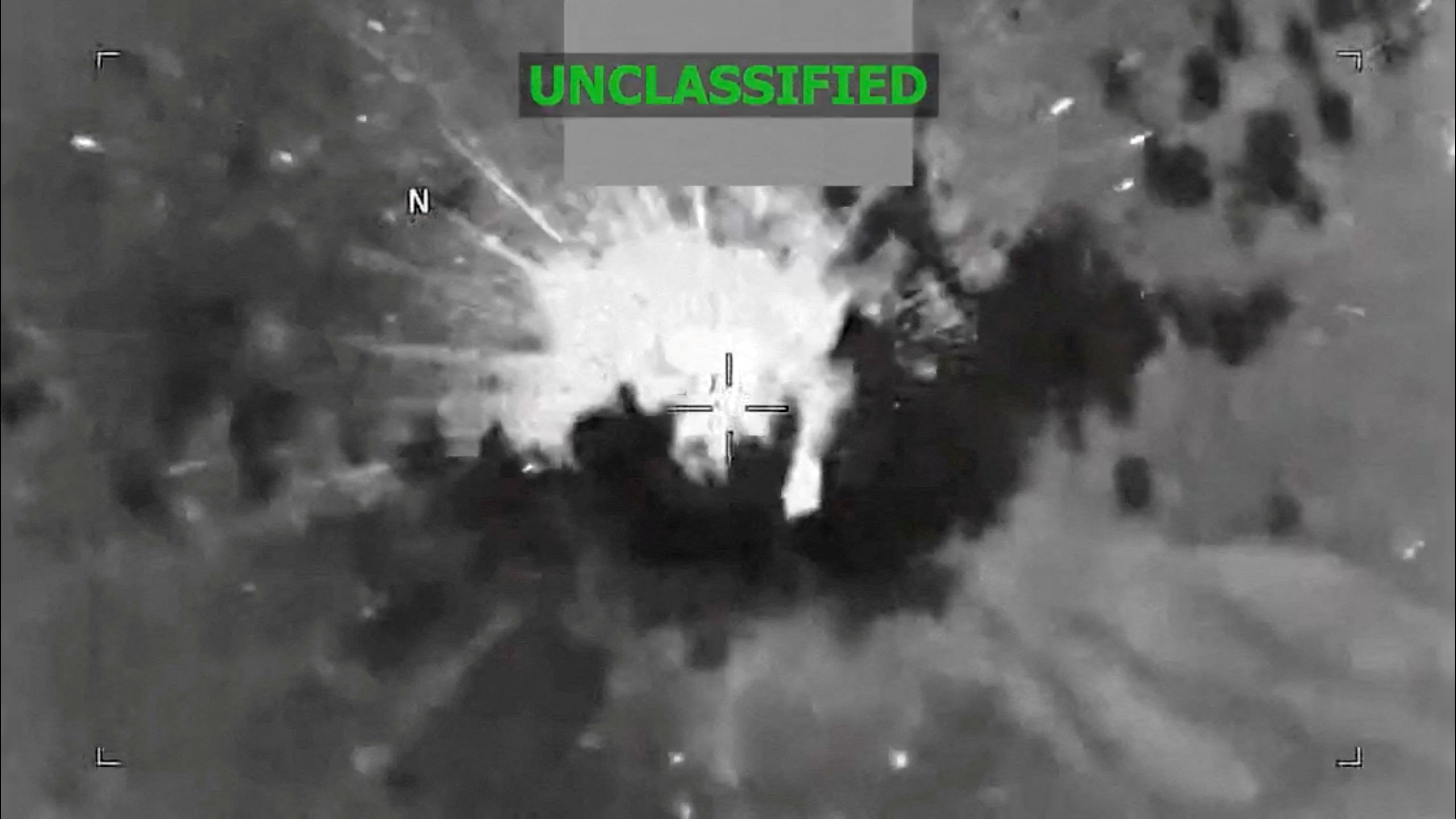 Grainy aerial video still of a fireball erupting from a small boat at sea