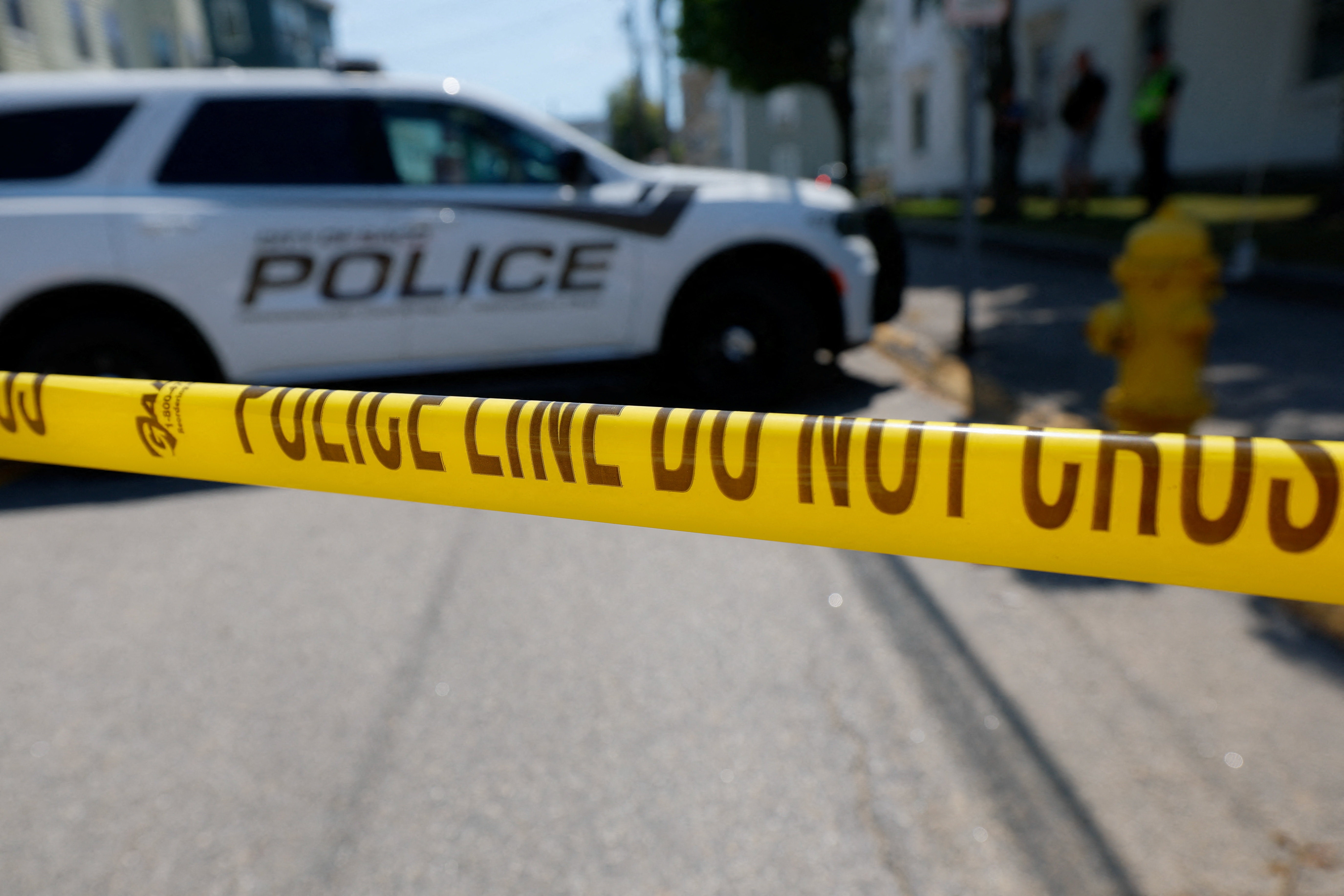 A yellow tape is seen as FBI agents and police officers work at a scene of a shooting
