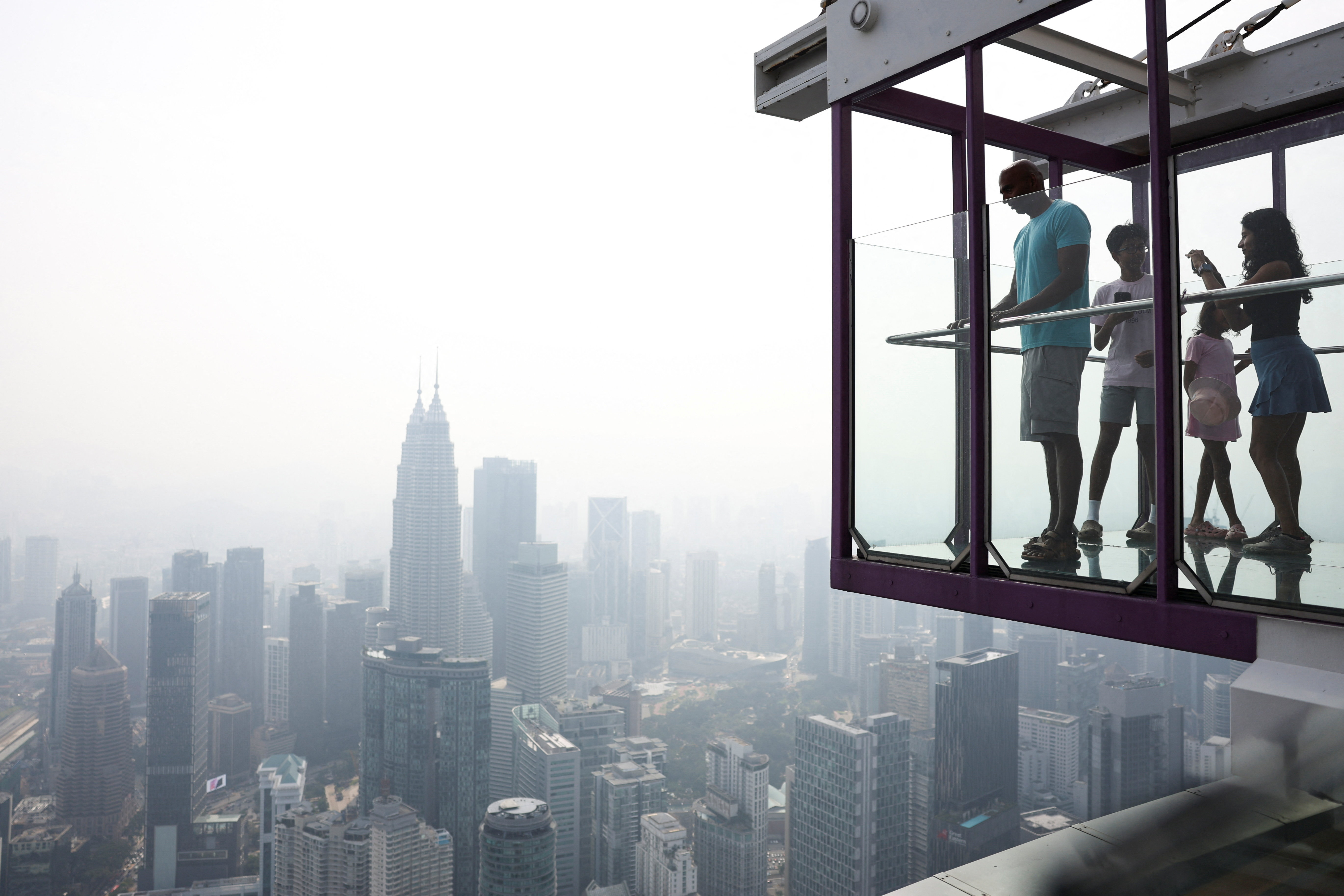 Tourists look at the city-centre skyline, shrouded in haze from wildfires in Indonesia, in Kuala Lumpur, Malaysia, August 12, 2026.