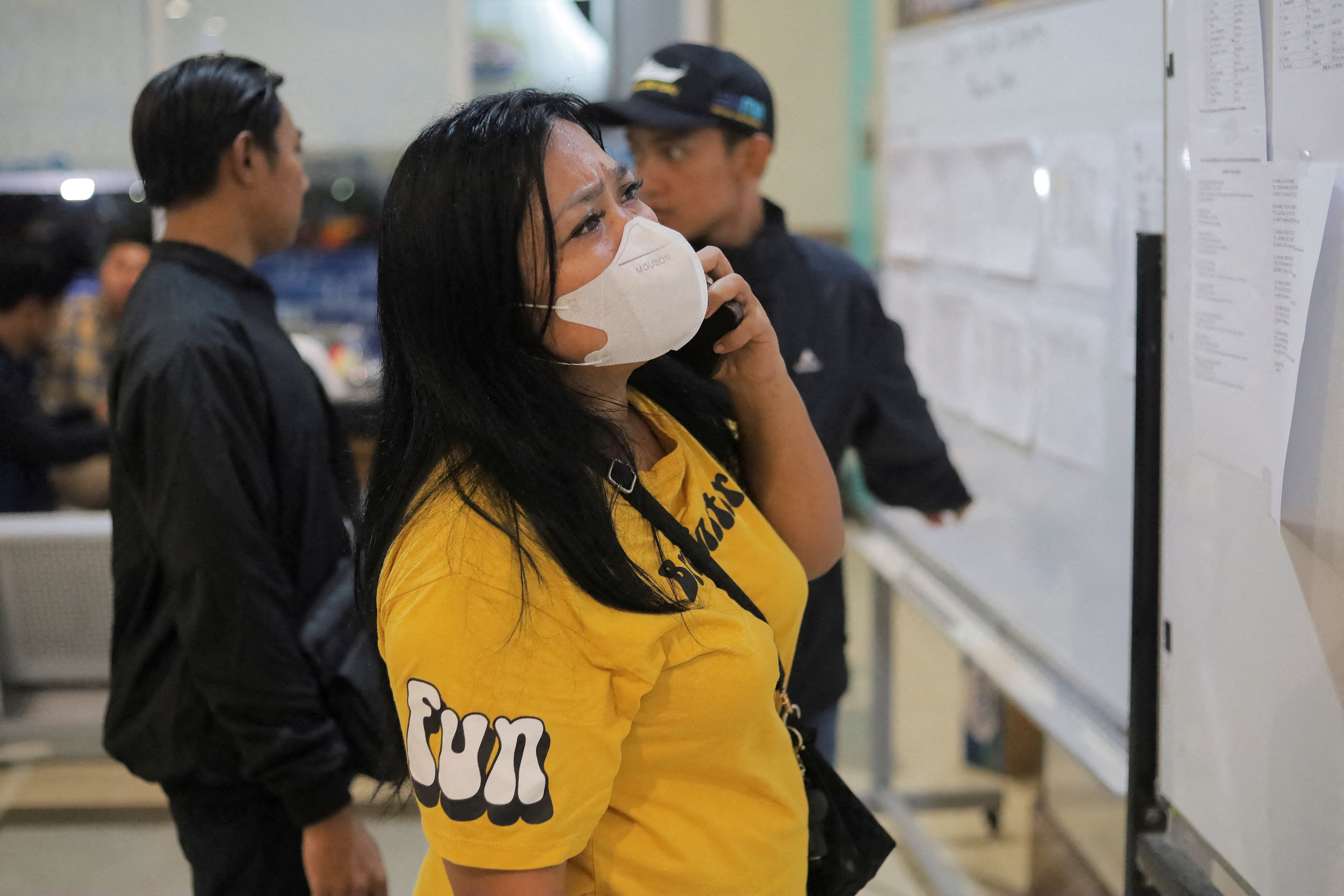 A woman holds a phone to her ear while waiting in a crowded port terminal.