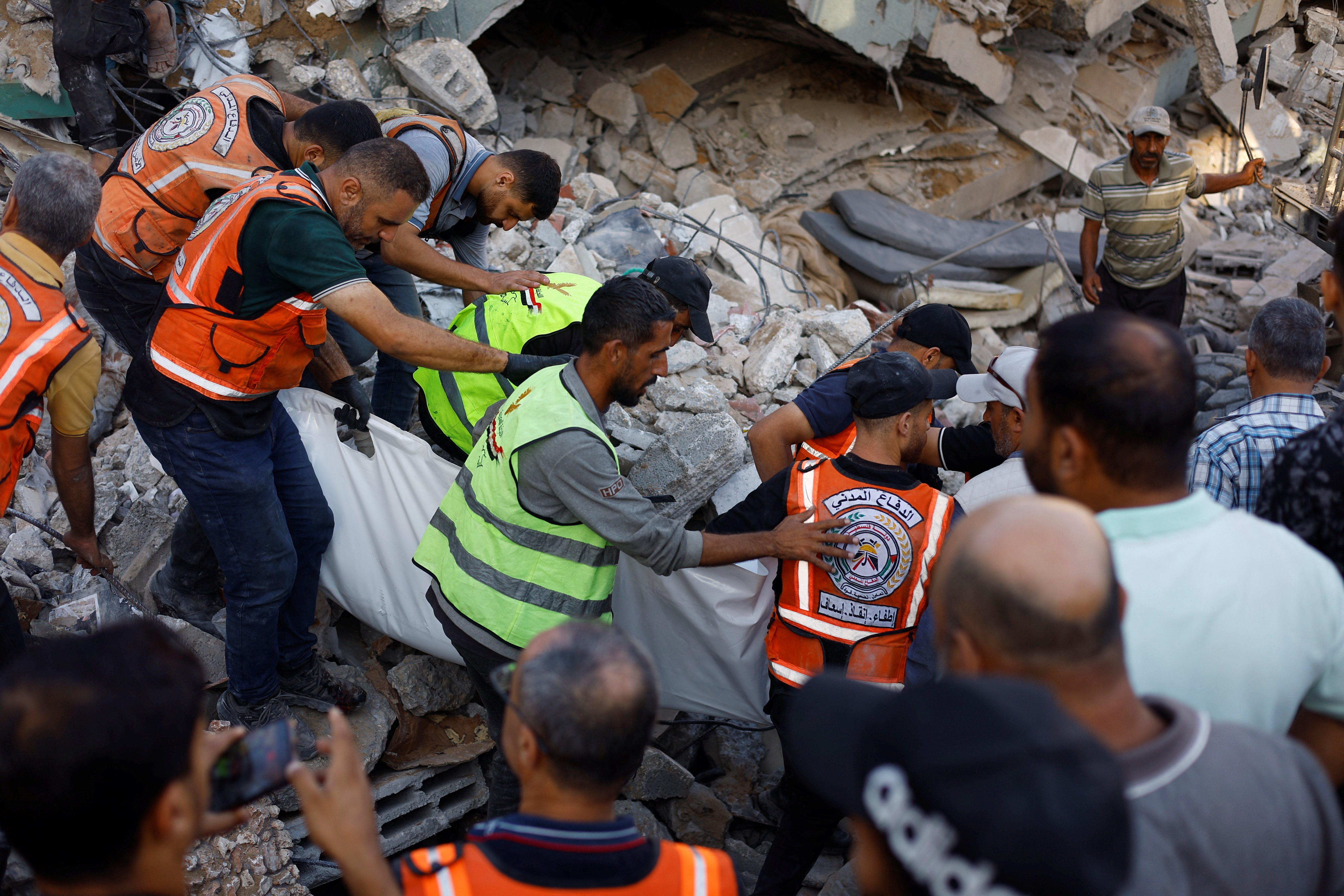 Civil Defence workers attempt to rescue people trapped beneath the rubble