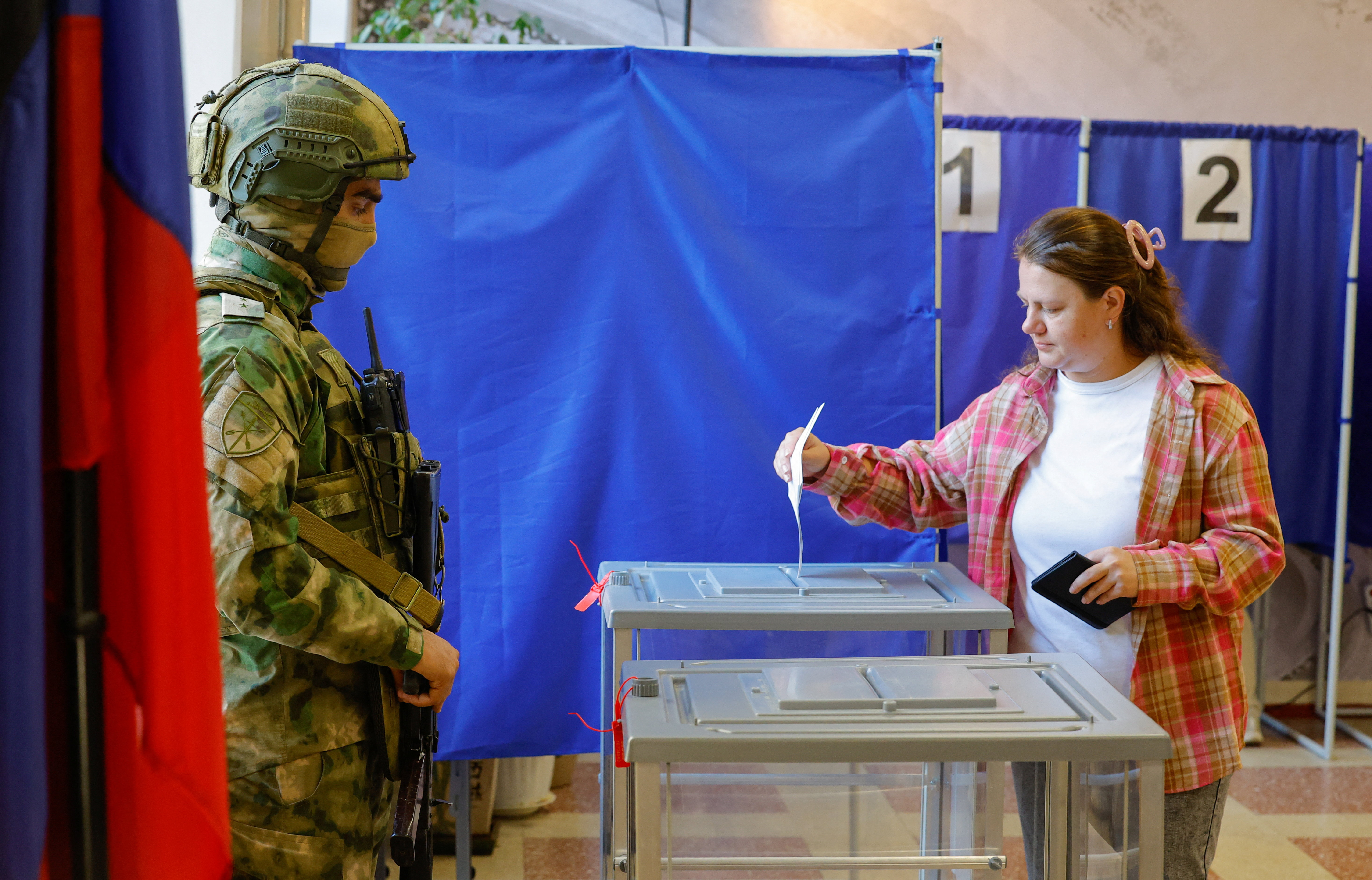 A woman casts her ballot next to a serviceman securing a polling station in Donetsk, Russian-controlled Ukraine, September 18, 2026 [Alexander Ermochenko/Reuters]