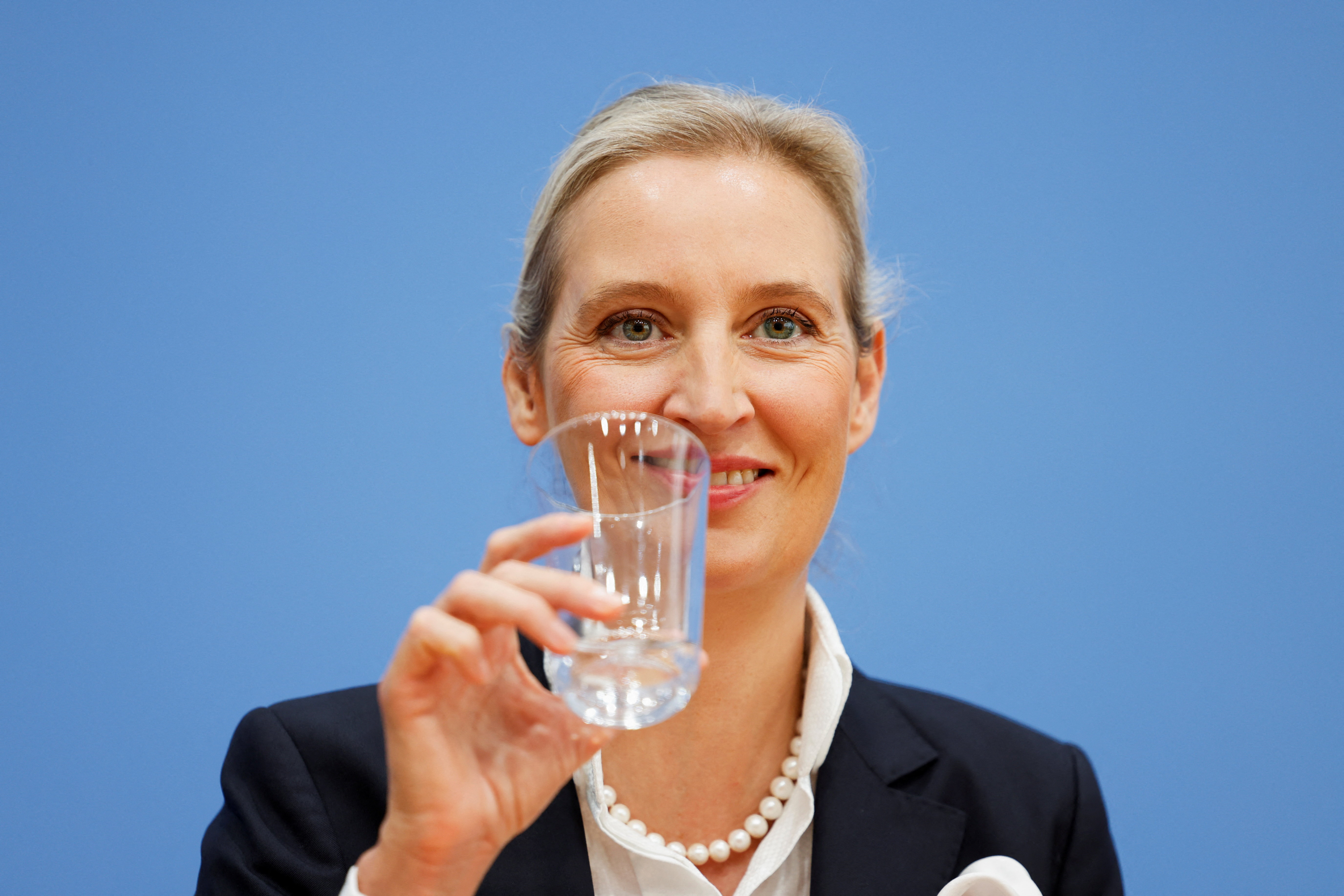 AfD co-leader Alice Weidel holds a glass during a news conference.