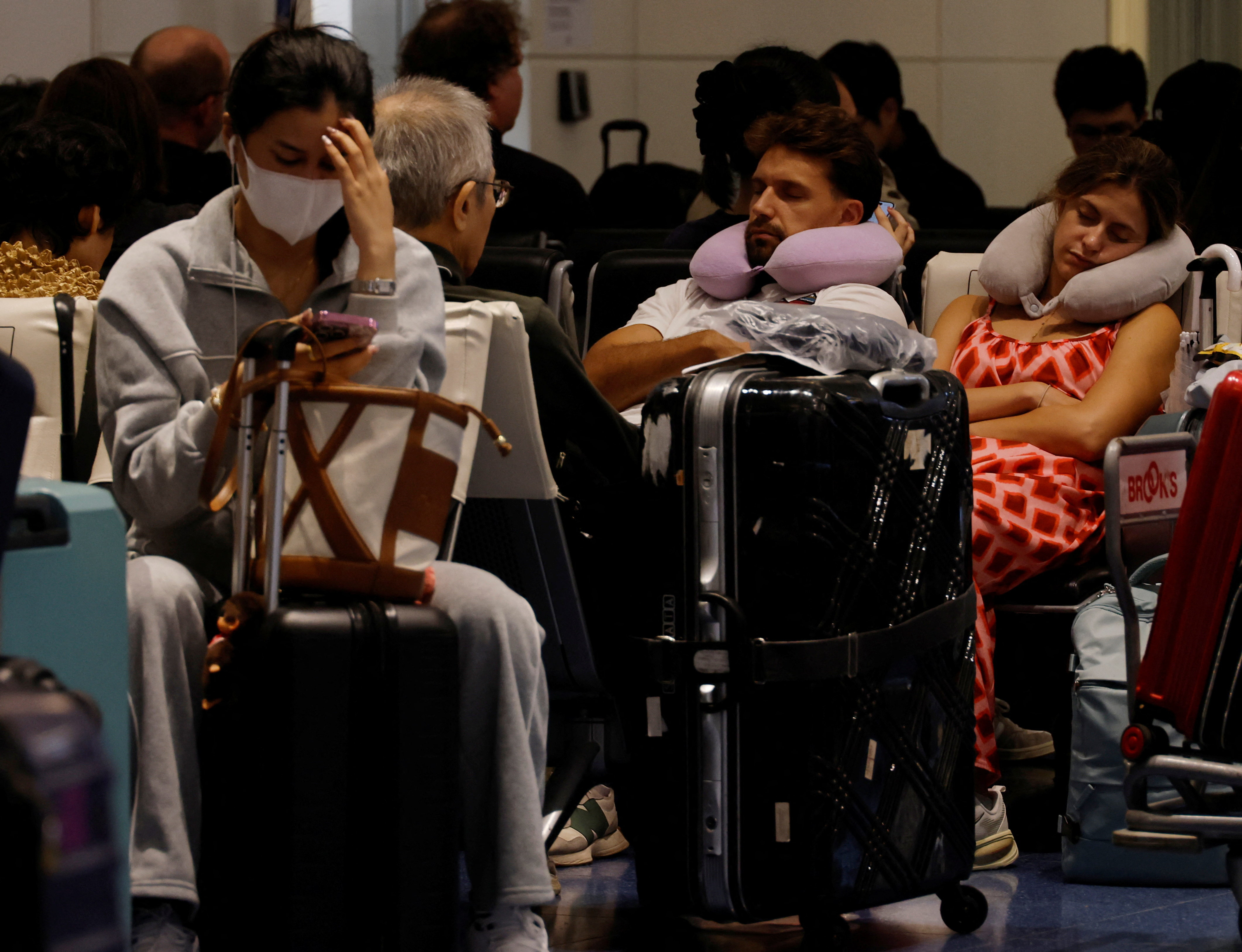 Passengers rest at Haneda airport in Tokyo, Japan, as many flights are delayed and cancelled because of Typhoon Dujuan, September 21, 2026