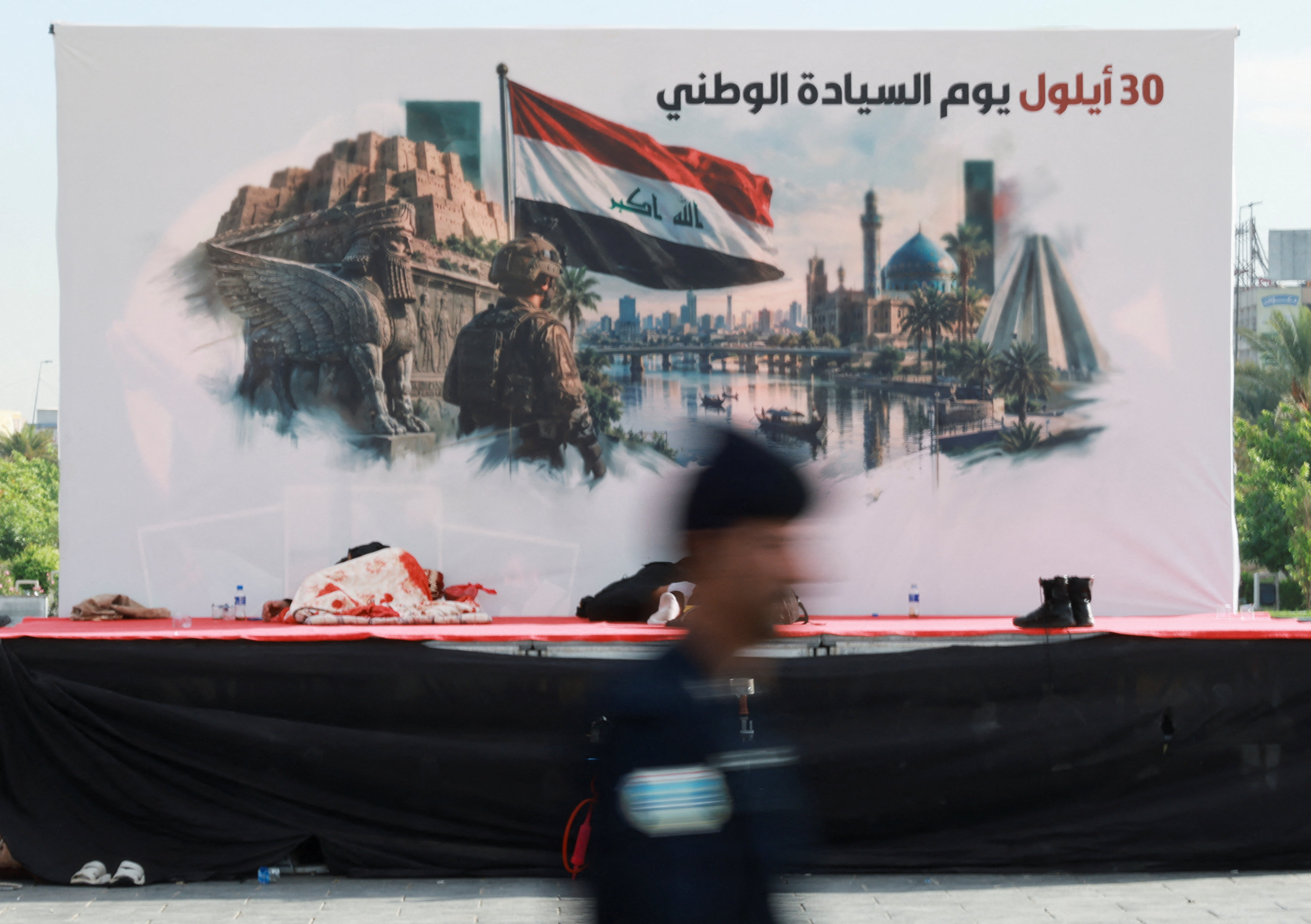 A person walks past a stage with a banner for Sovereignty Day in Baghdad, Iraq, September 30, 2026. Sovereignty Day marks the withdrawal of US-led coalition forces from Iraq, thereby ending more than two decades of military presence there. REUTERS/Ahmed Saad