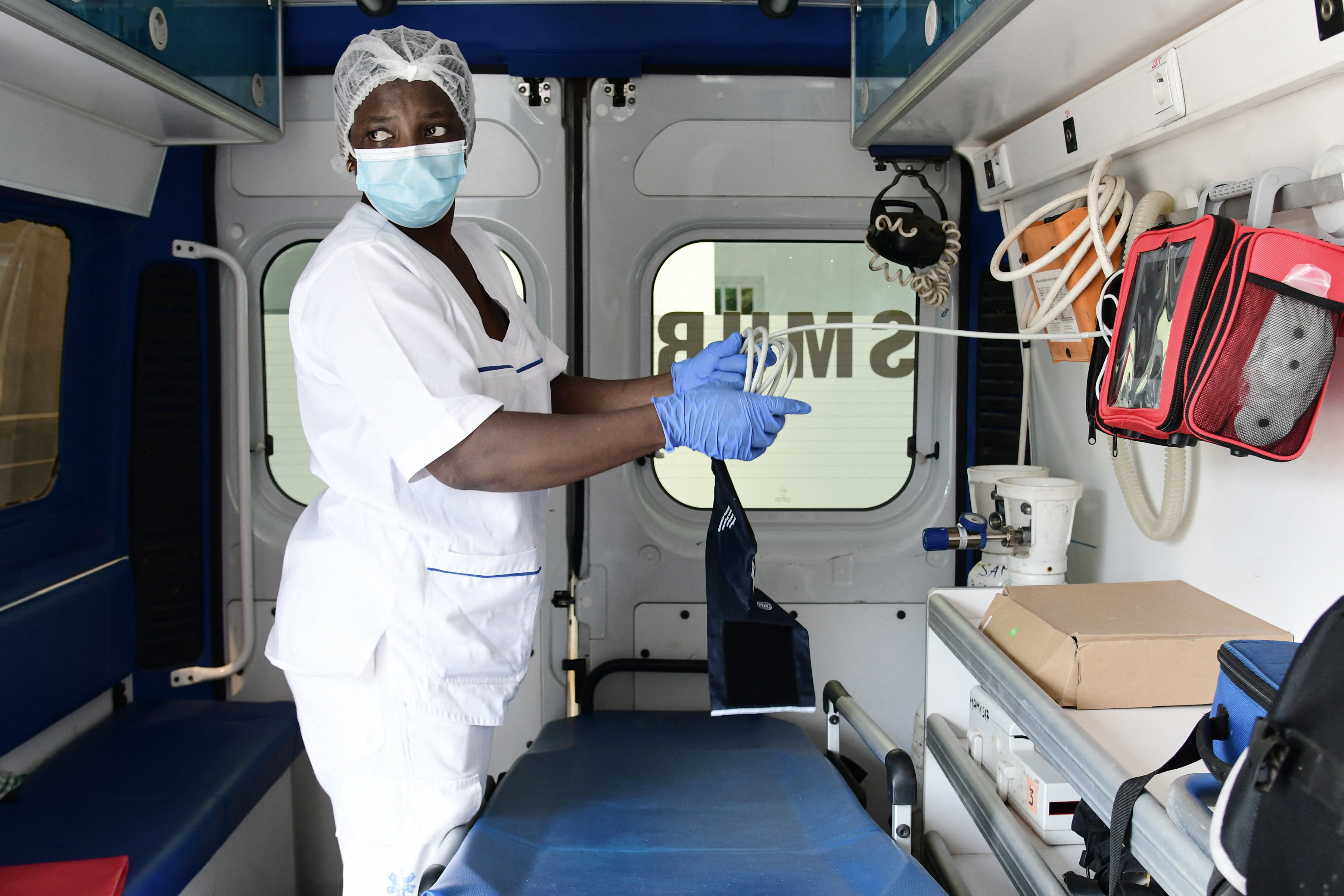 A nurse prepares medical equipment in an ambulance.