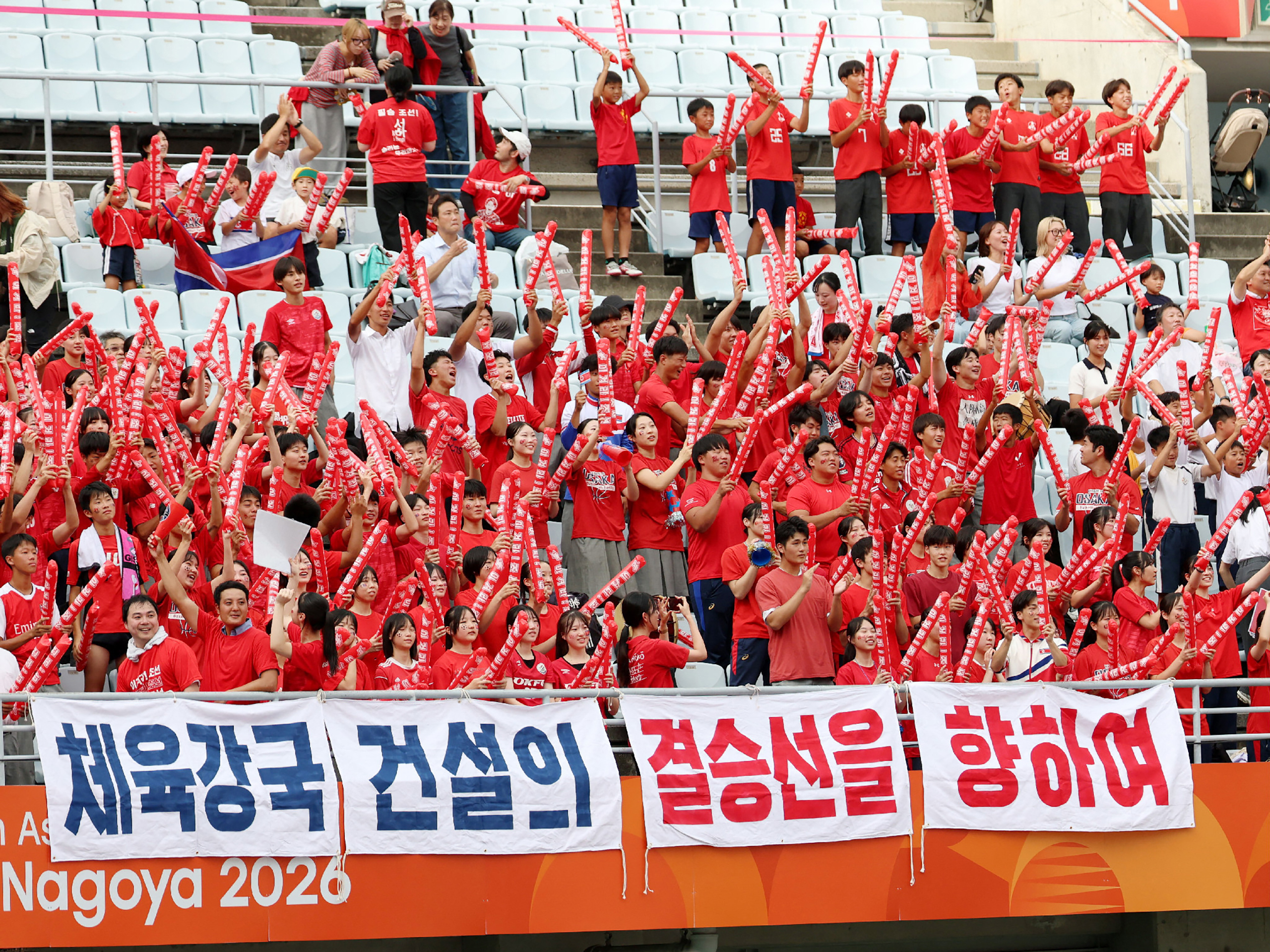 North Korean fans cheer during the 2026 Asian Games women's group B football match against Bangladesh at Yanmar Stadium Nagai in Osaka on September 14, 2026. North Korea's formidable women's football team launched their Asian Games with a 10-0 hammering of Bangladesh, cheered on by several hundred pro-Pyongyang fans in Osaka. (Photo by JIJI Press / AFP) / Japan OUT