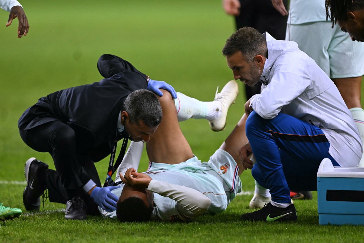 France's forward #10 Kylian Mbappe (C) receives medical assistance after scoring the opening goal and a leg pain