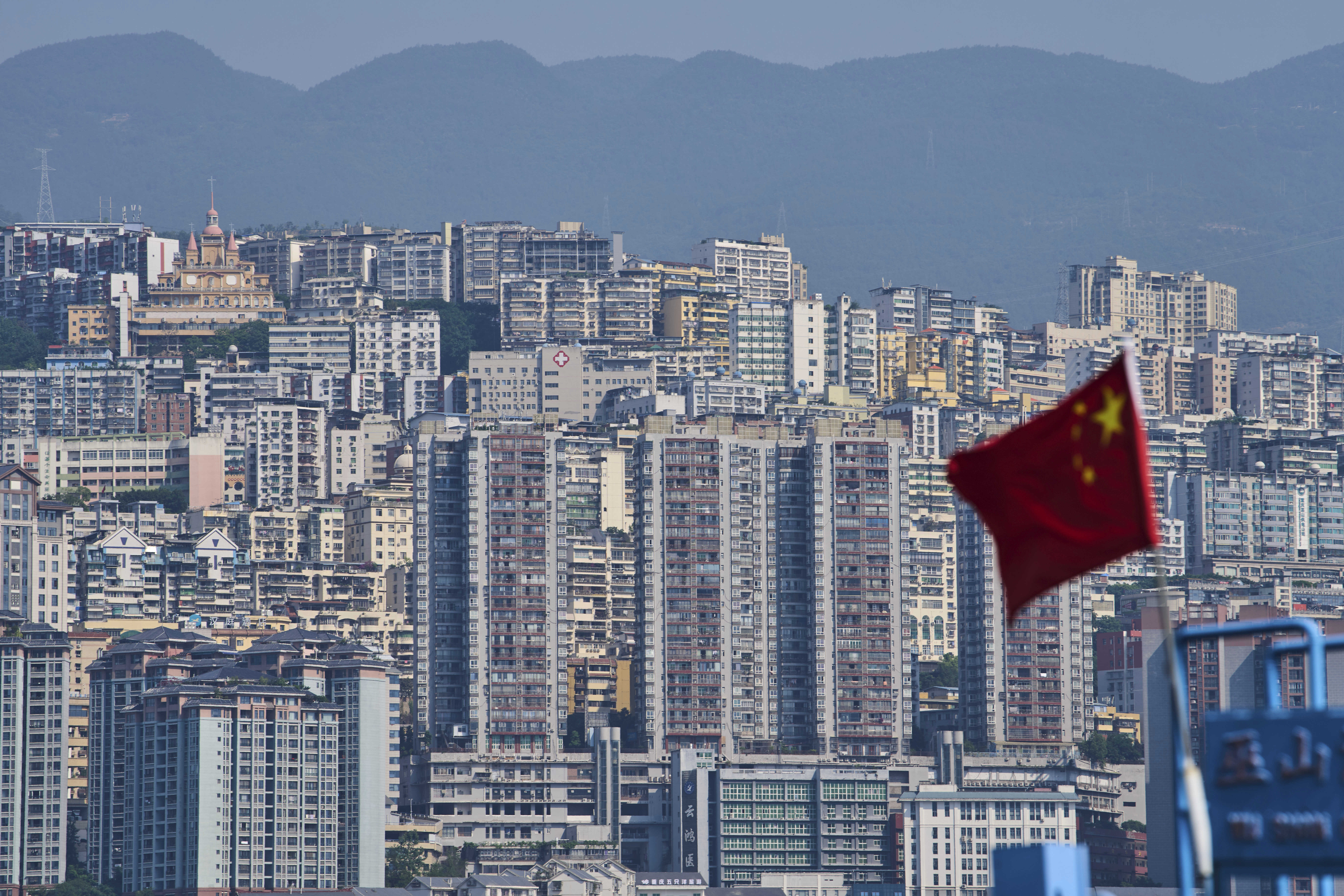 A Chinese national flag flutters against the high-rise residential buildings in Wushan county, in southwest China’s Chongqing Municipality, Wednesday, May 21, 2025. Chongqing is one of the major inland regions that the canal will connect to Southeast Asia