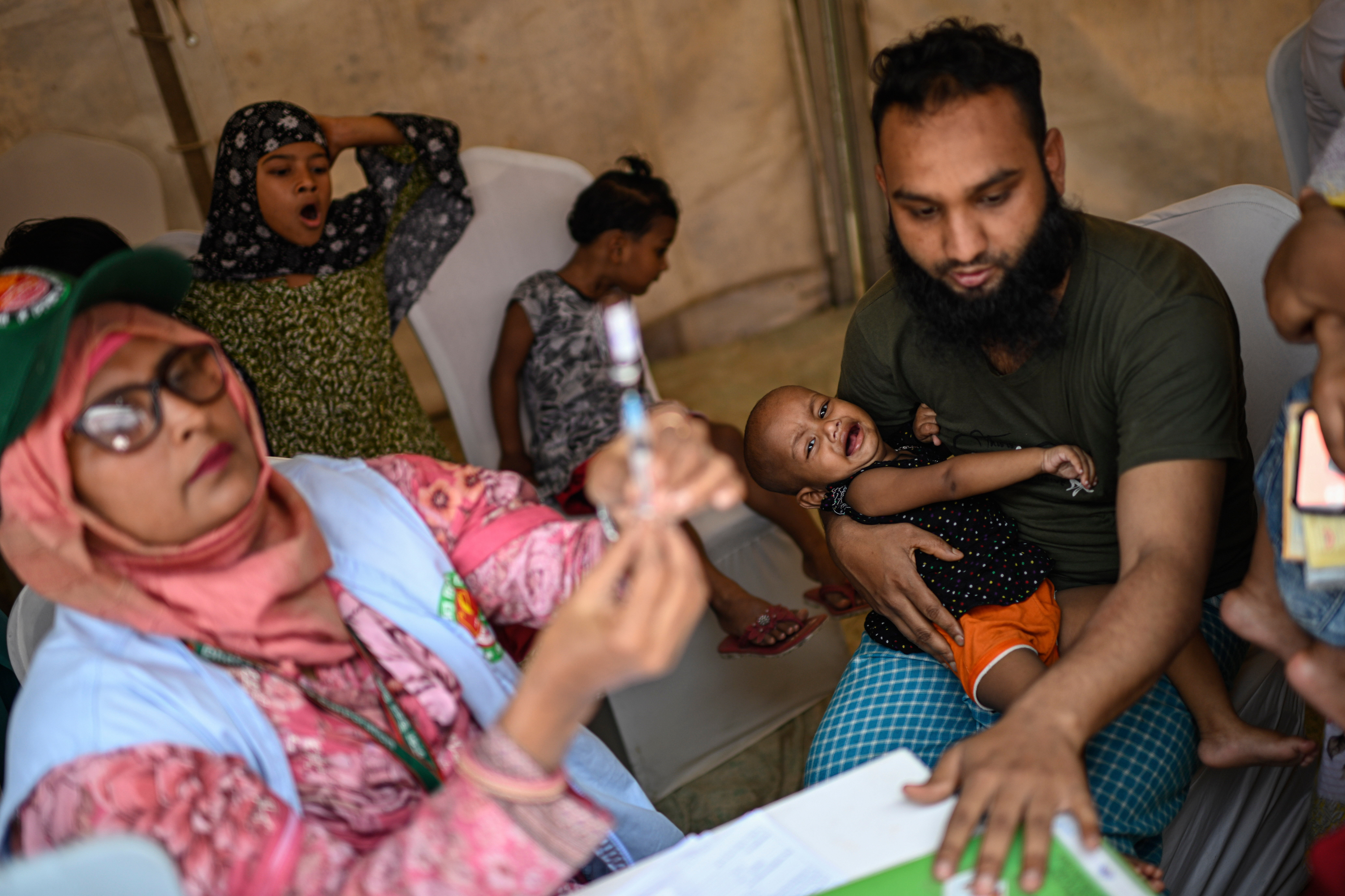 A healthcare worker prepares a measles vaccine while a father holds his young daughter at a vaccination center in Dhaka, Bangladesh, Sunday, April 12, 2026. (AP Photo/Mahmud Hossain Opu)