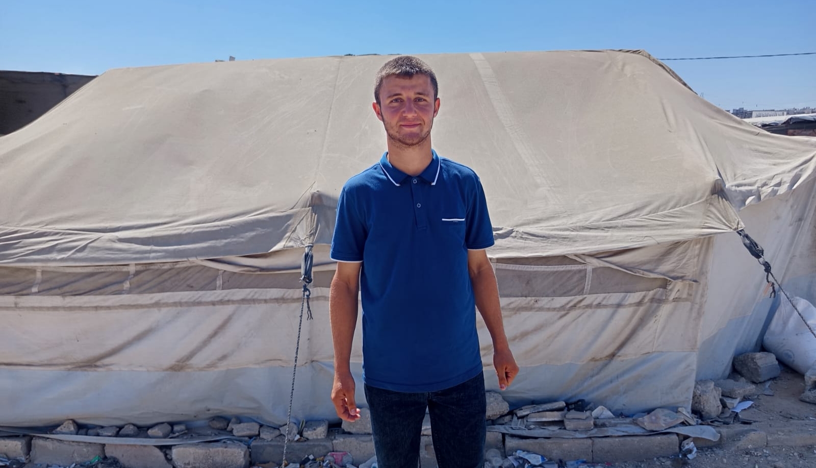 Ahmed Al-Batsh stands outside his shelter in Gaza. Despite losing his mother in the war and facing heavy financial pressures, he is preparing to marry [Alaa Dmeida/Al Jazeera]