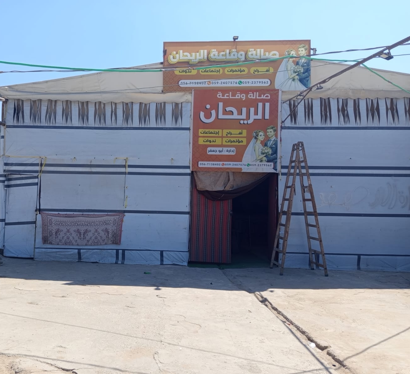 The exterior of Al-Reihan Hall, a wedding evenue that has been rebuilt with tarpaulins and wood [Alaa Dmeida/Al Jazeera]