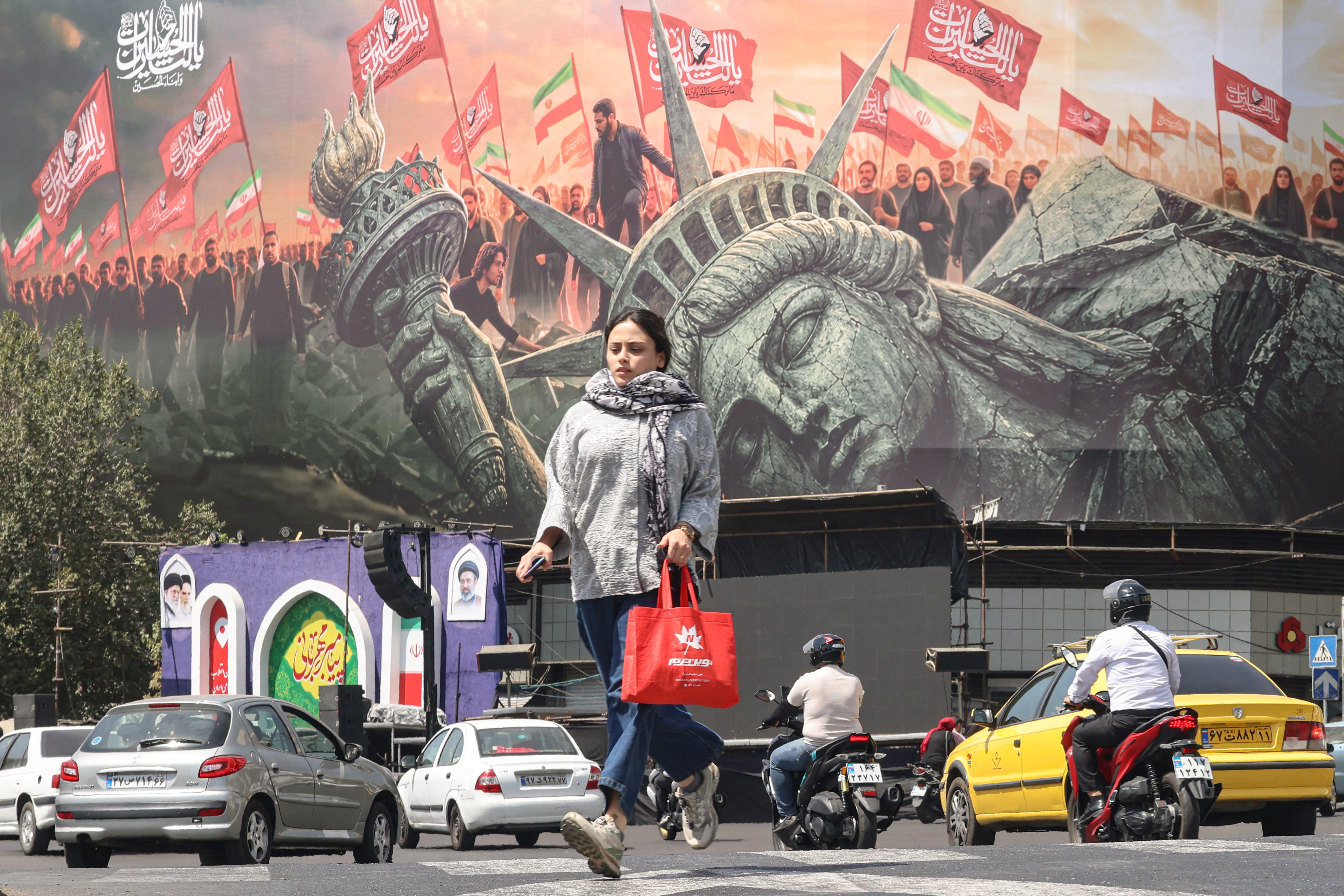 People walk past an anti-US billboard at Enghelab Square in central Tehran on September 2, 2026.