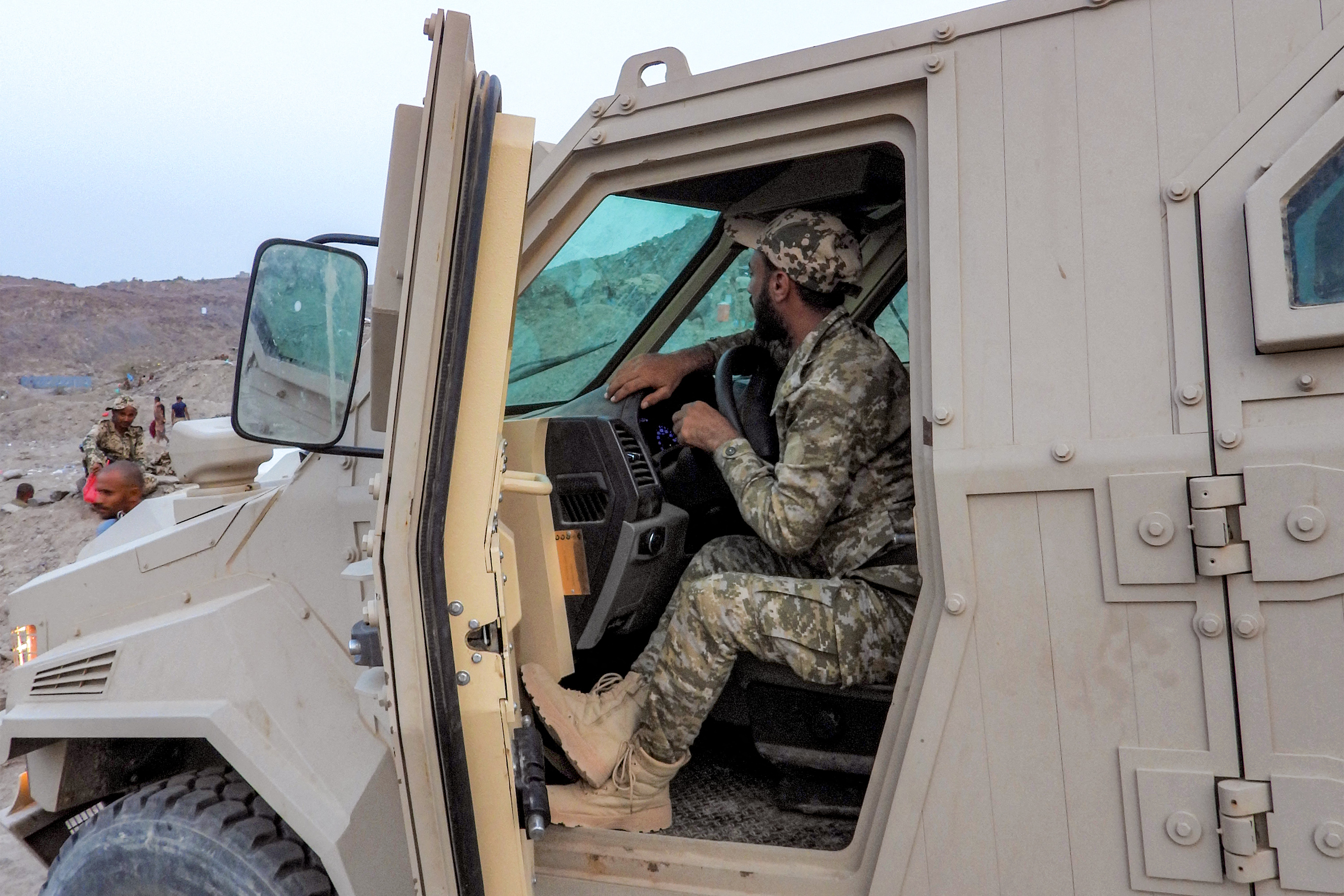 A soldier sits in an armoured vehicle.