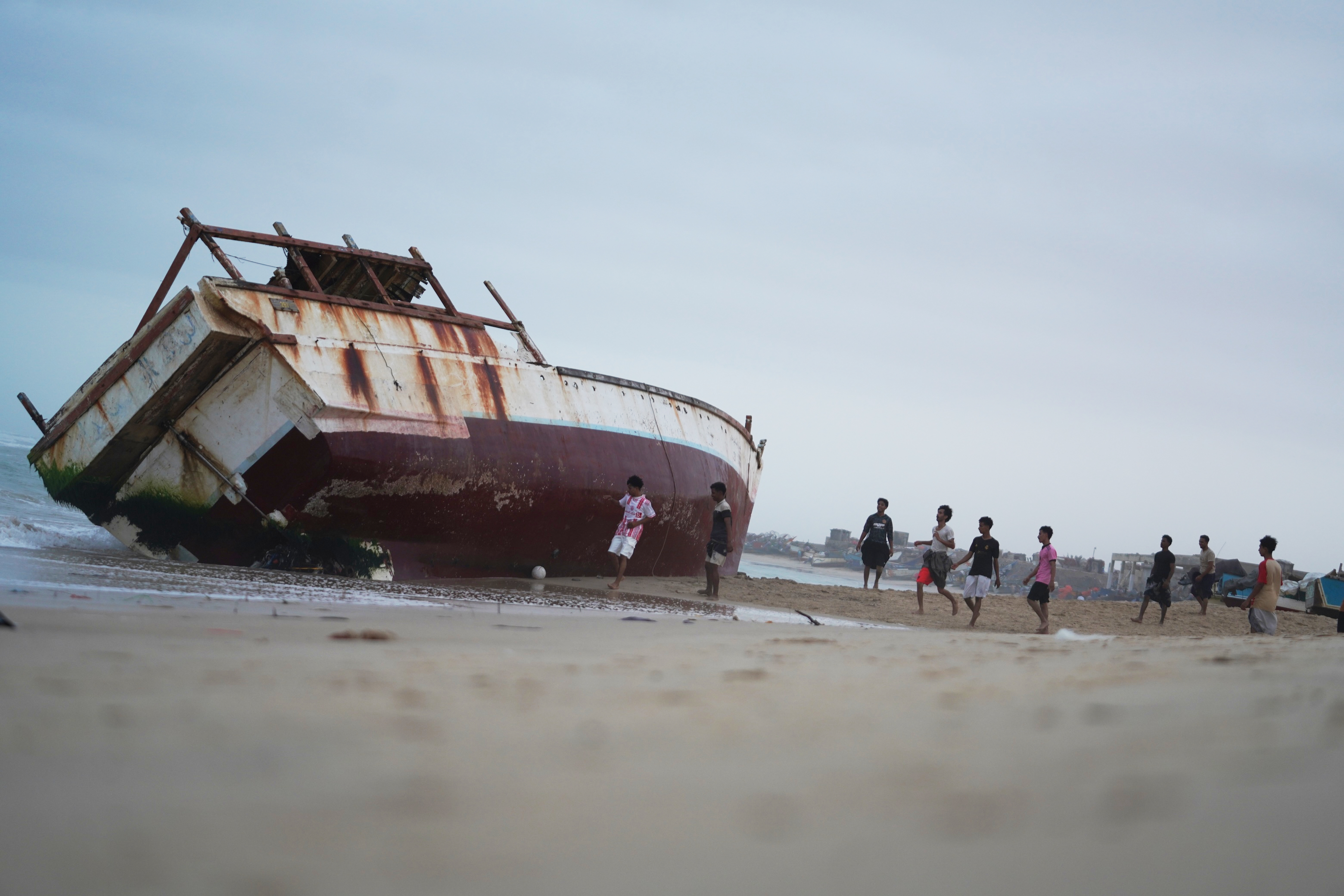 Young men play near a beached fishing boat at a site in Al-Ghaydah district, in Al Mukalla, Yemen, Sunday, Sept. 6, 2026. (AP Photo/Abdulnasser Alseddik)