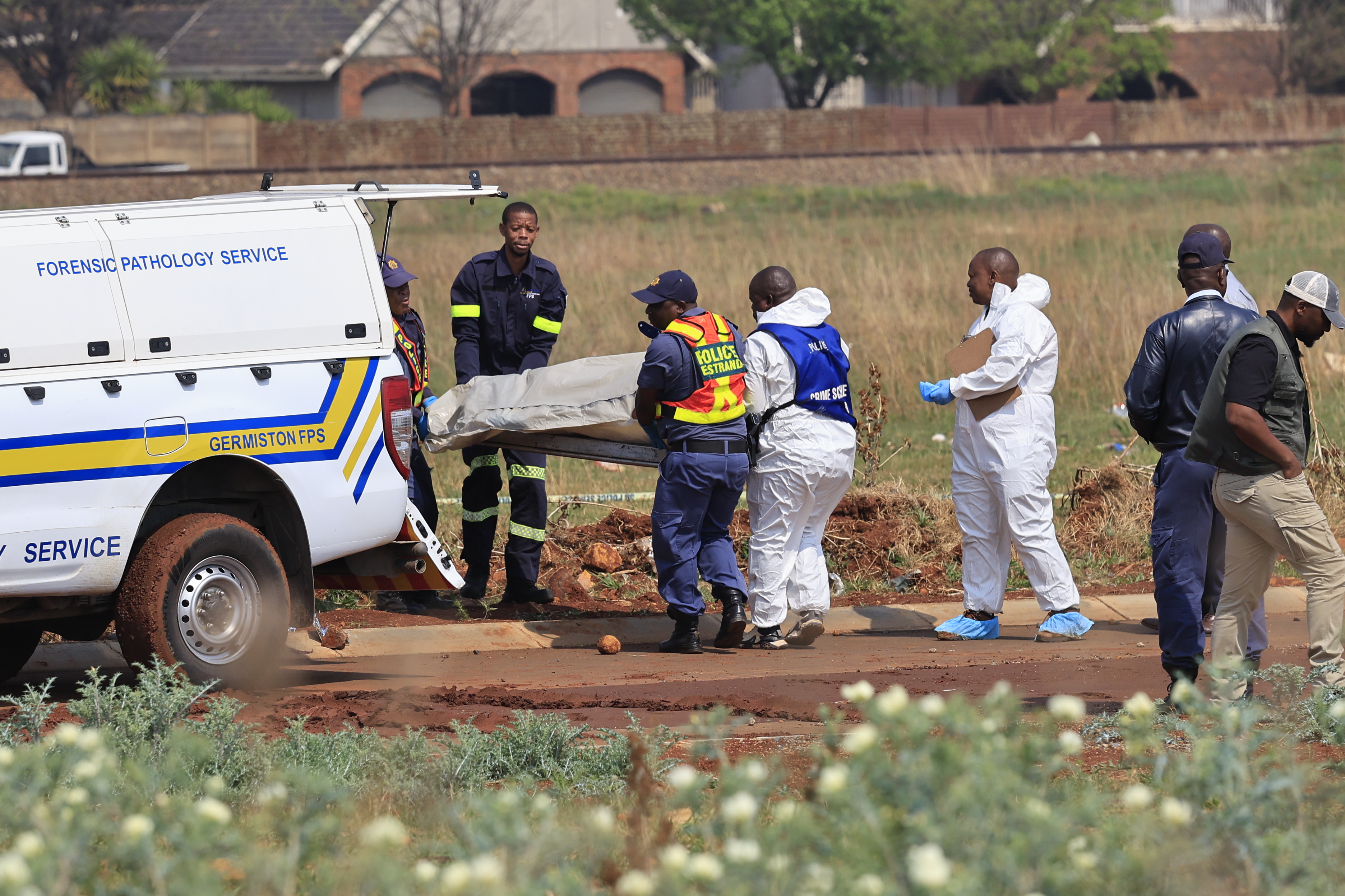 epa13245362 Members of the SAPS (South African Police Service) and state pathologists inspect the body of one of the women found dumped on the side of a road in Boksburg, Johannesburg, South Africa, 17 September 2026. The remains of nine murdered women have been found in recent weeks as SAPS tries to arrest the killer. EPA/Kim Ludbrook