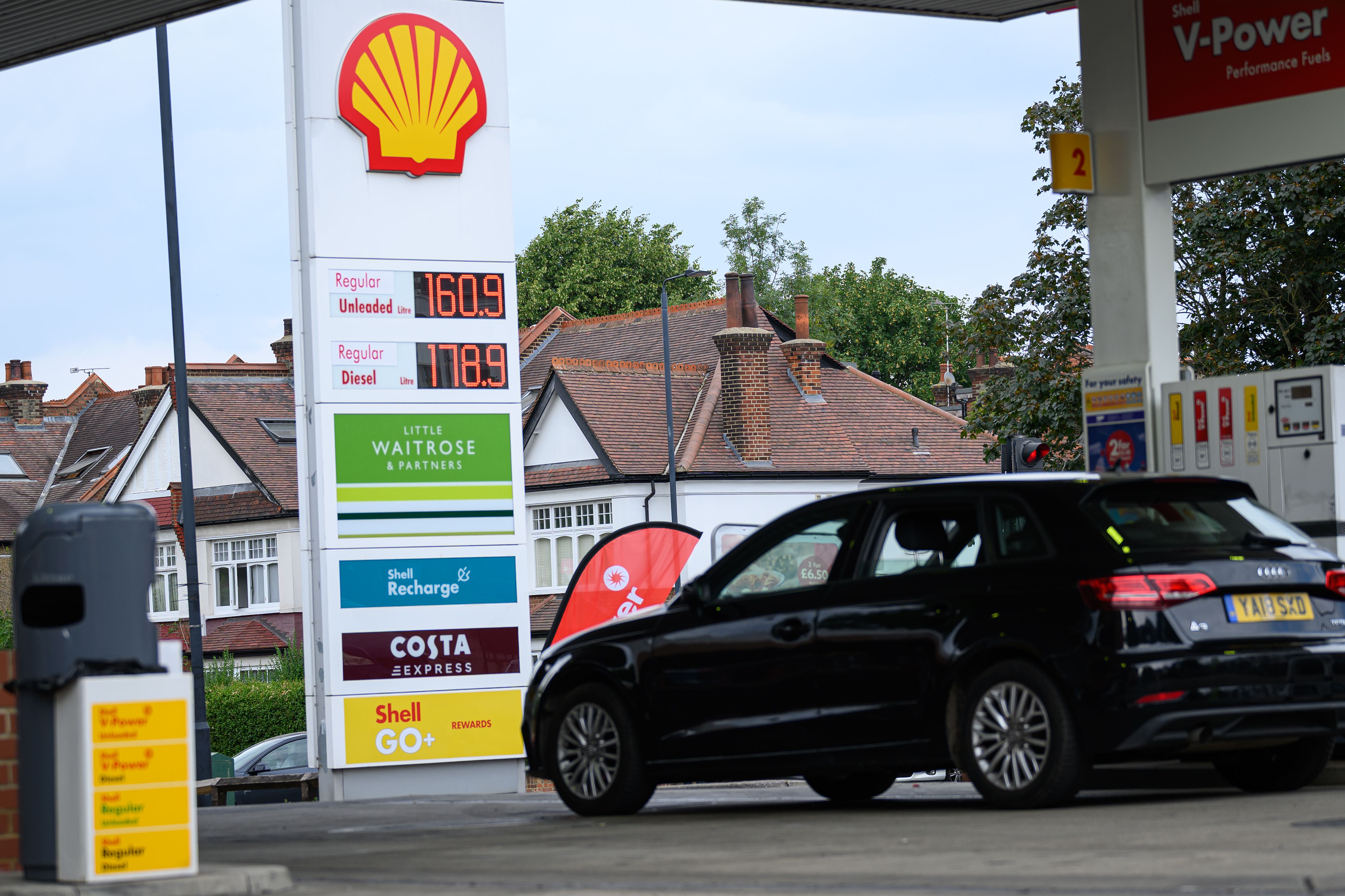Fuel prices are displayed on a digital board at a petrol station.