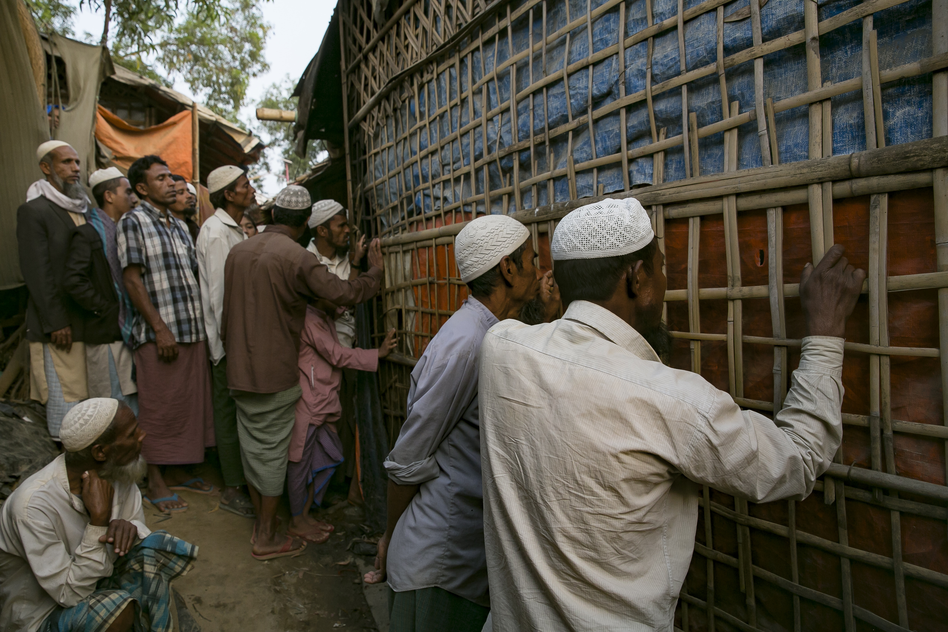 COX'S BAZAR, BANGLADESH - JANUARY 23: People peer through holes in the wall of a restaurant to watch the ICJ hearing in a Rohingya refugee camp on January 23, 2020 in Cox's Bazar, Bangladesh. On Thursday, the International Court of Justice ordered Myanmar to take emergency measures to prevent genocide of the Rohingya. In a unanimously-ruled order  the court upheld the provisions of the 1948 Genocide Convention - saying Myanmar had "caused irreparable damage to the rights of the Rohingya". (Photo by Allison Joyce/Getty Images)