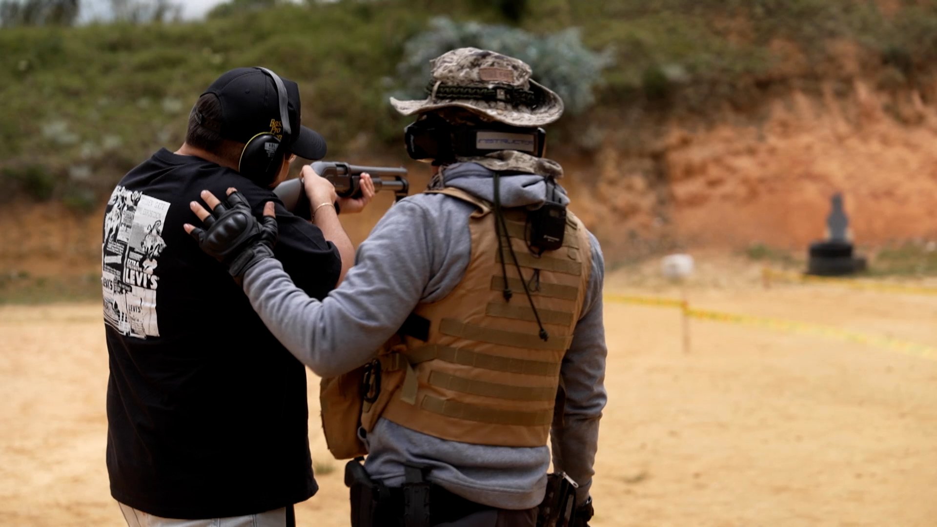 A man is holding a gun and training how to use it, aiming at a target