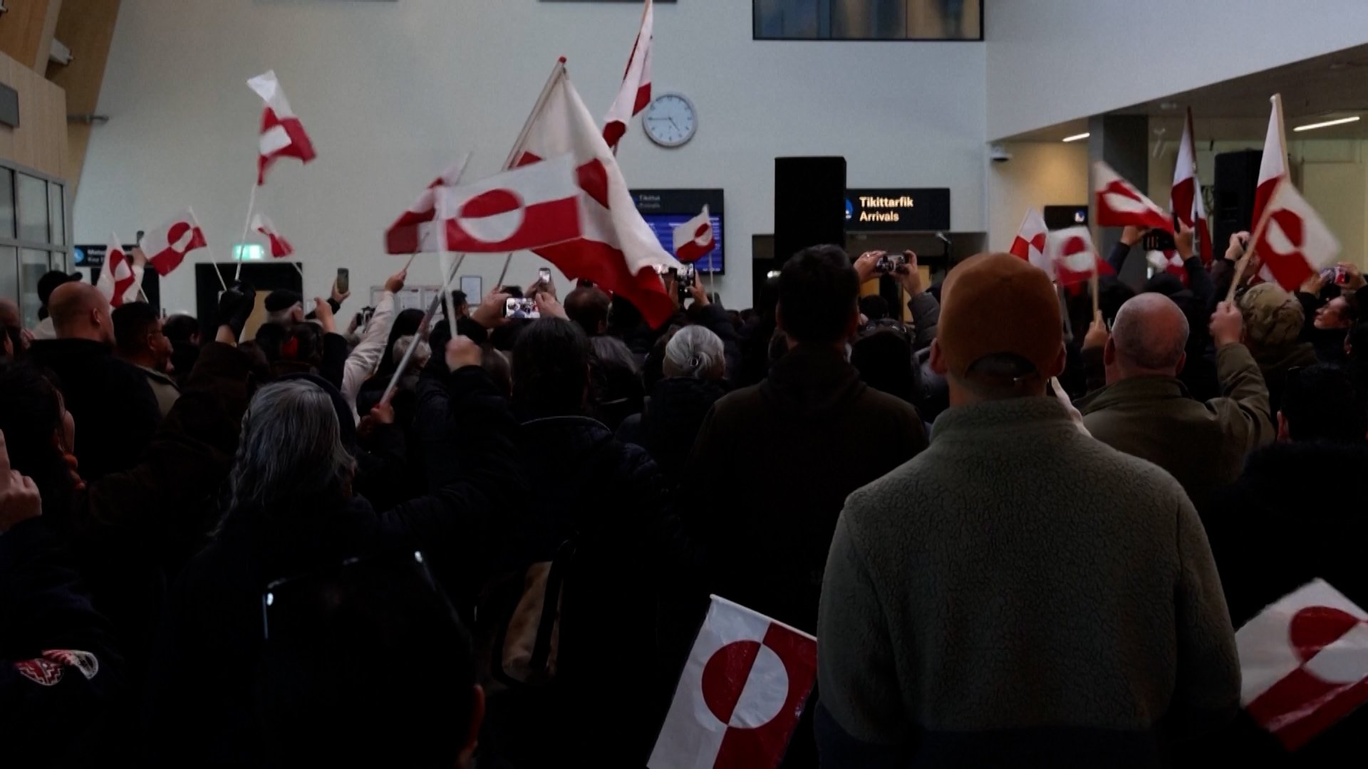 supporters waving flags and cheering for Greenland's delegation