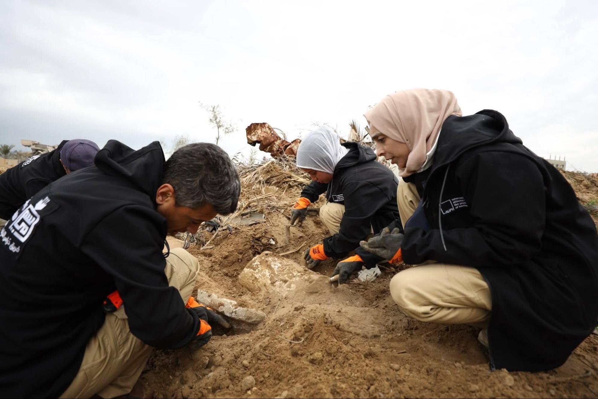 Volunteers and specialists use basic tools to carefully excavate a buried artifact during field survey operations in Gaza [Enas Naser/Al Jazeera]