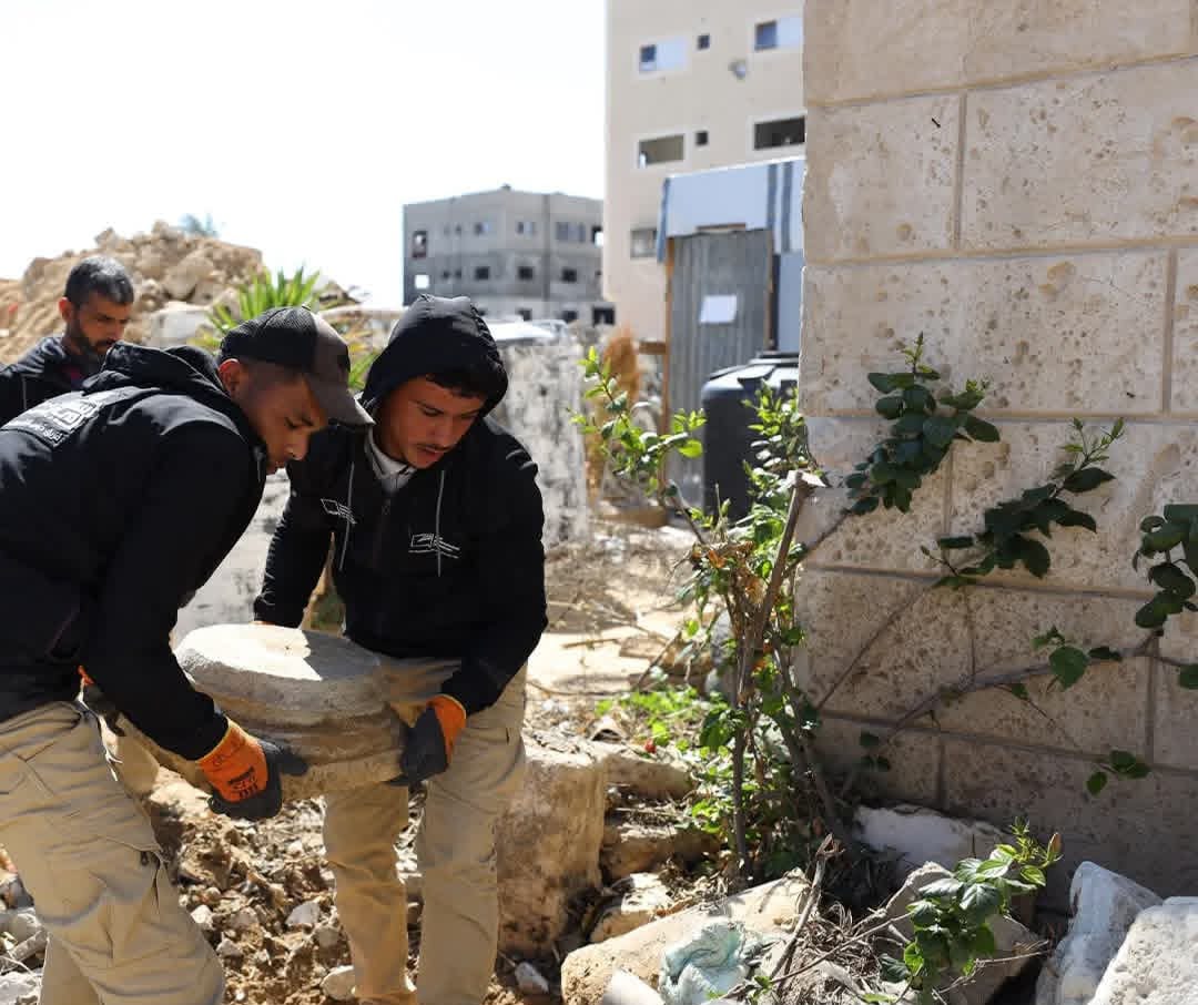 Members of the "Guardians of Heritage" team inspect and clean recovered archaeological pottery inside a temporary storage tent in Al-Mawasi, southern Gaza Strip. [Enas Naser/Al Jazeera]