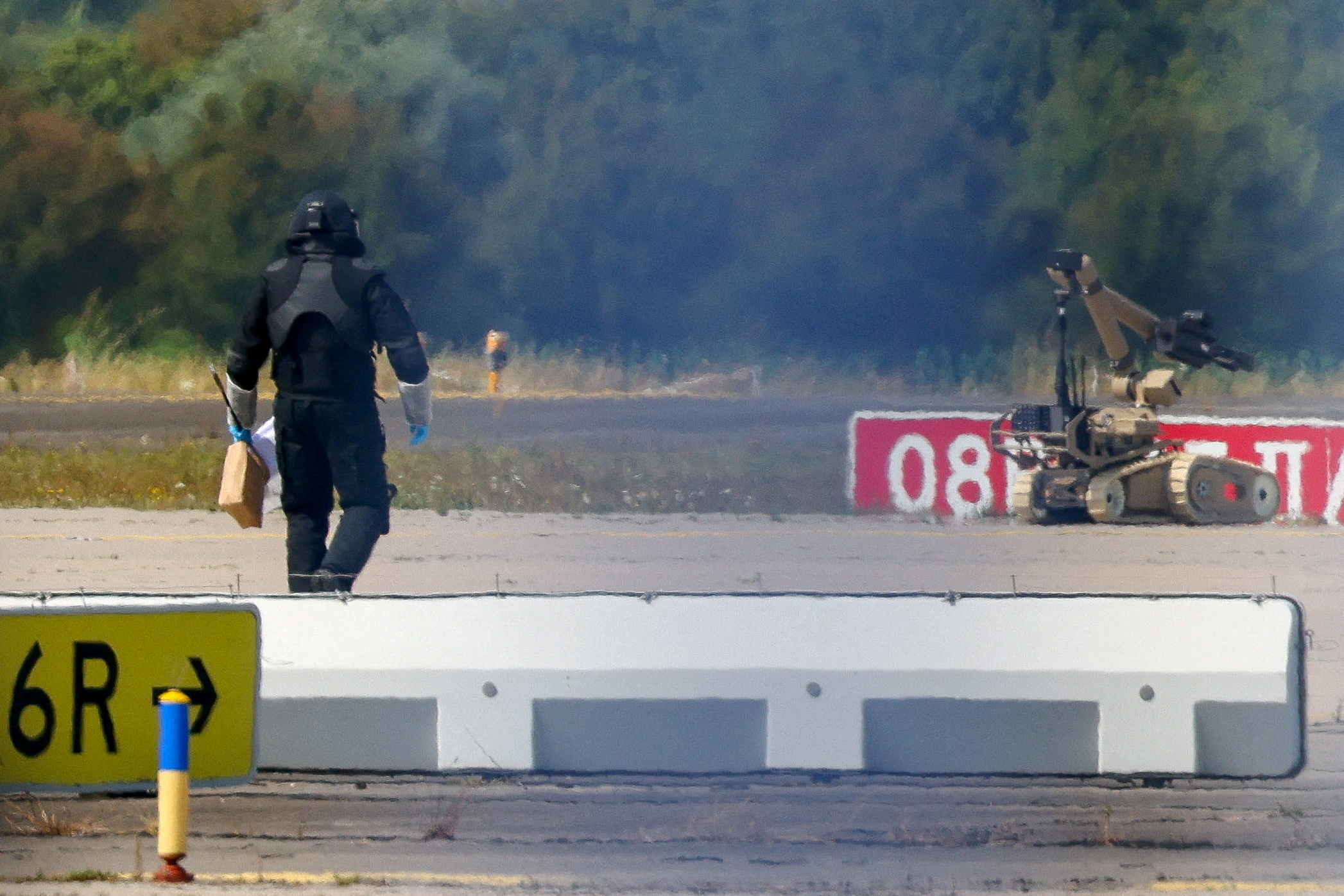 A police officer walks next to an explosive-disarming robot at Leipzig/Halle Airport in Schkeuditz, Germany, after a drone was discovered
