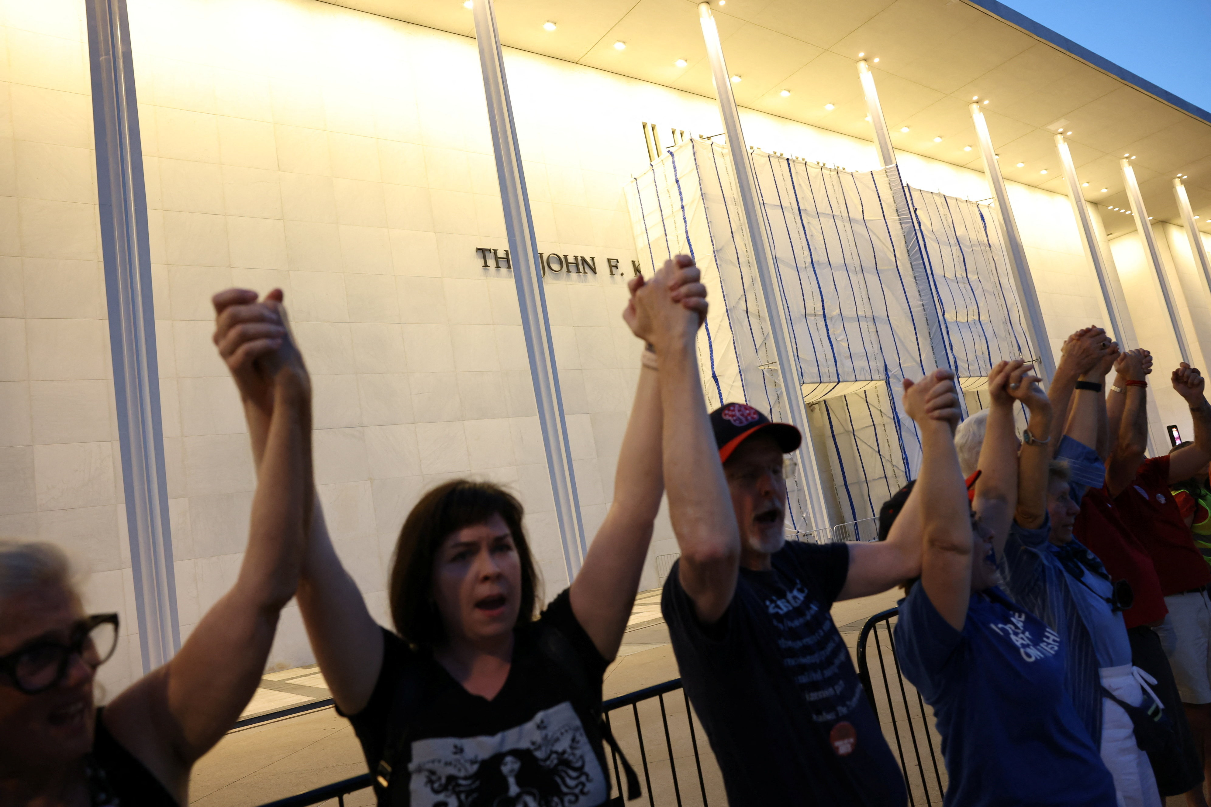 Cassandra Corcoran, Leslie Cook and other protestors hold hands as they denounce the Kennedy Center board's vote to close one of the nation's premier performing arts venues, outside the John F. Kennedy Memorial Center for the Performing Arts in Washington, D.C., US, September 18, 2026. REUTERS/Leah Millis