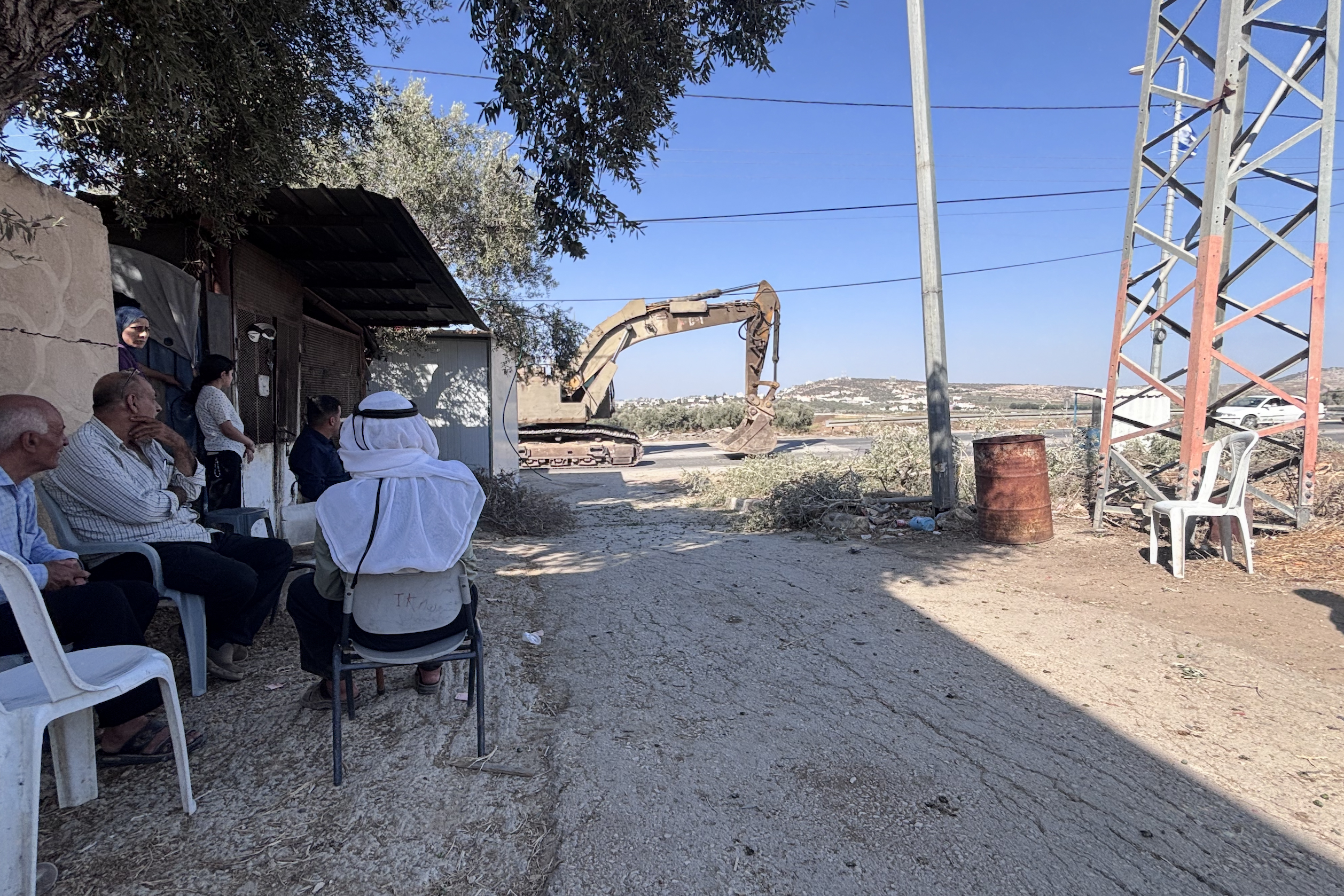 Members of the al-Fari family watch on as an Israeli bulldozer pass by [Al Jazeera]