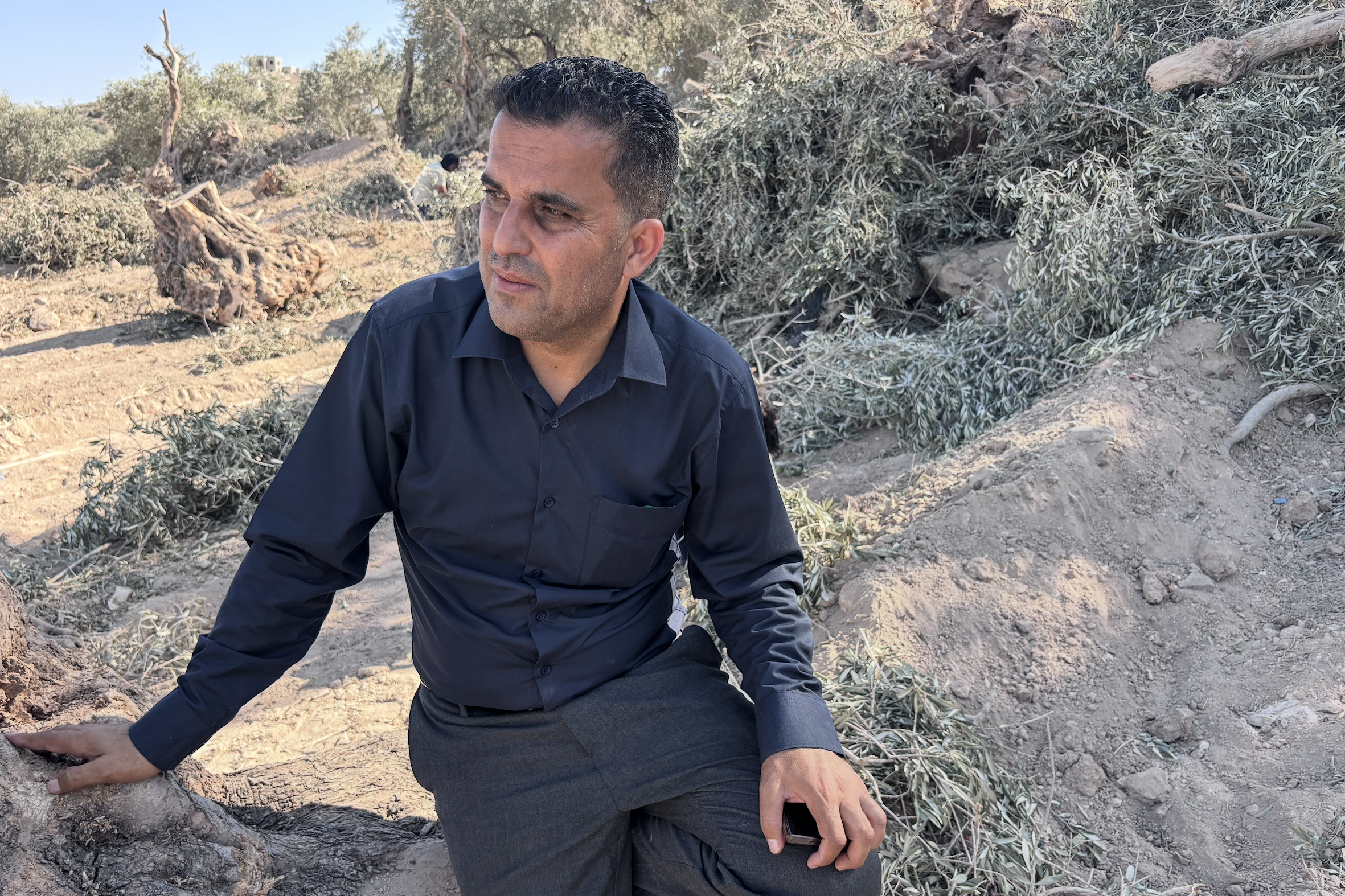 Khalil al-Fari surrounded by destroyed trees [Al Jazeera]