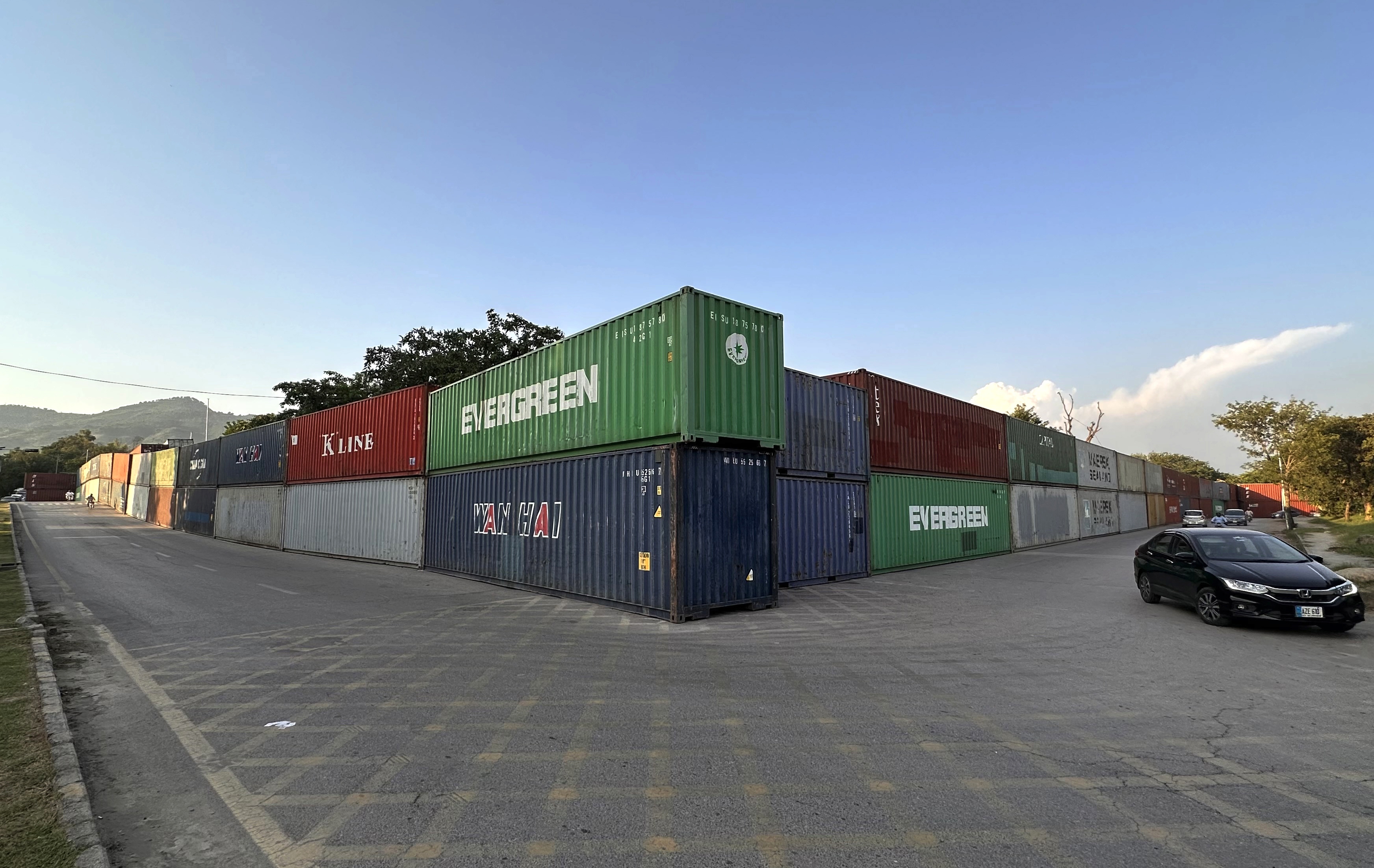 epa13248316 Commuters pass shipping containers lining Islamabads Red Zone, in Islamabad, Pakistan, 18 September 2026. Authorities have deployed containers and additional security personnel at key roads and entry points ahead of planned opposition protests and a Pakistan Tehreek-e-Insaf (PTI) long march scheduled for September 27, with the party demanding the release of former Prime Minister Khan. The security measures have disrupted traffic and raised concerns about restricted road access and the detention of commercial containers. EPA/SOHAIL SHAHZAD