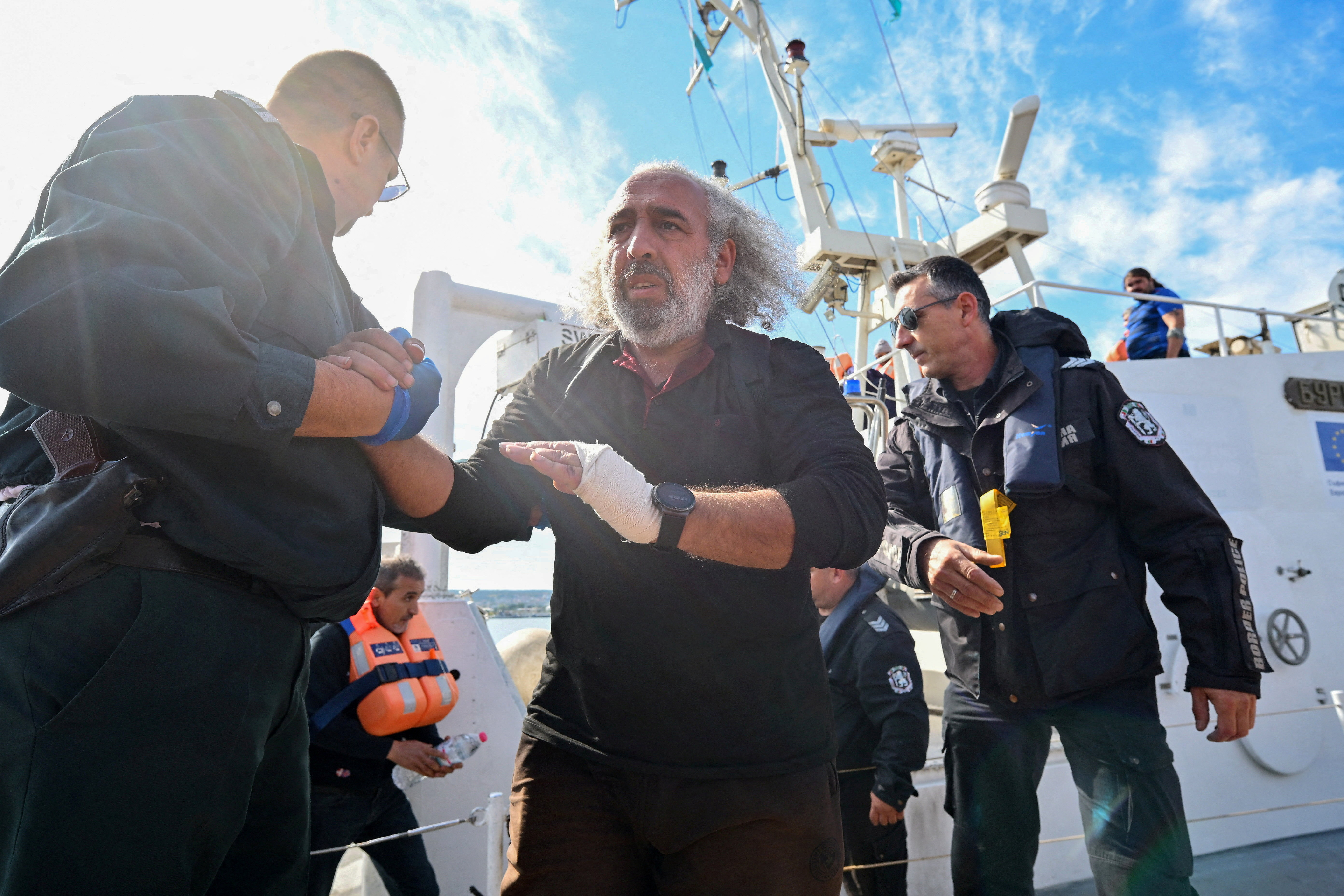 Crew members from a ship damaged in a drone attack disembark from a Bulgarian border police vessel in Varna
