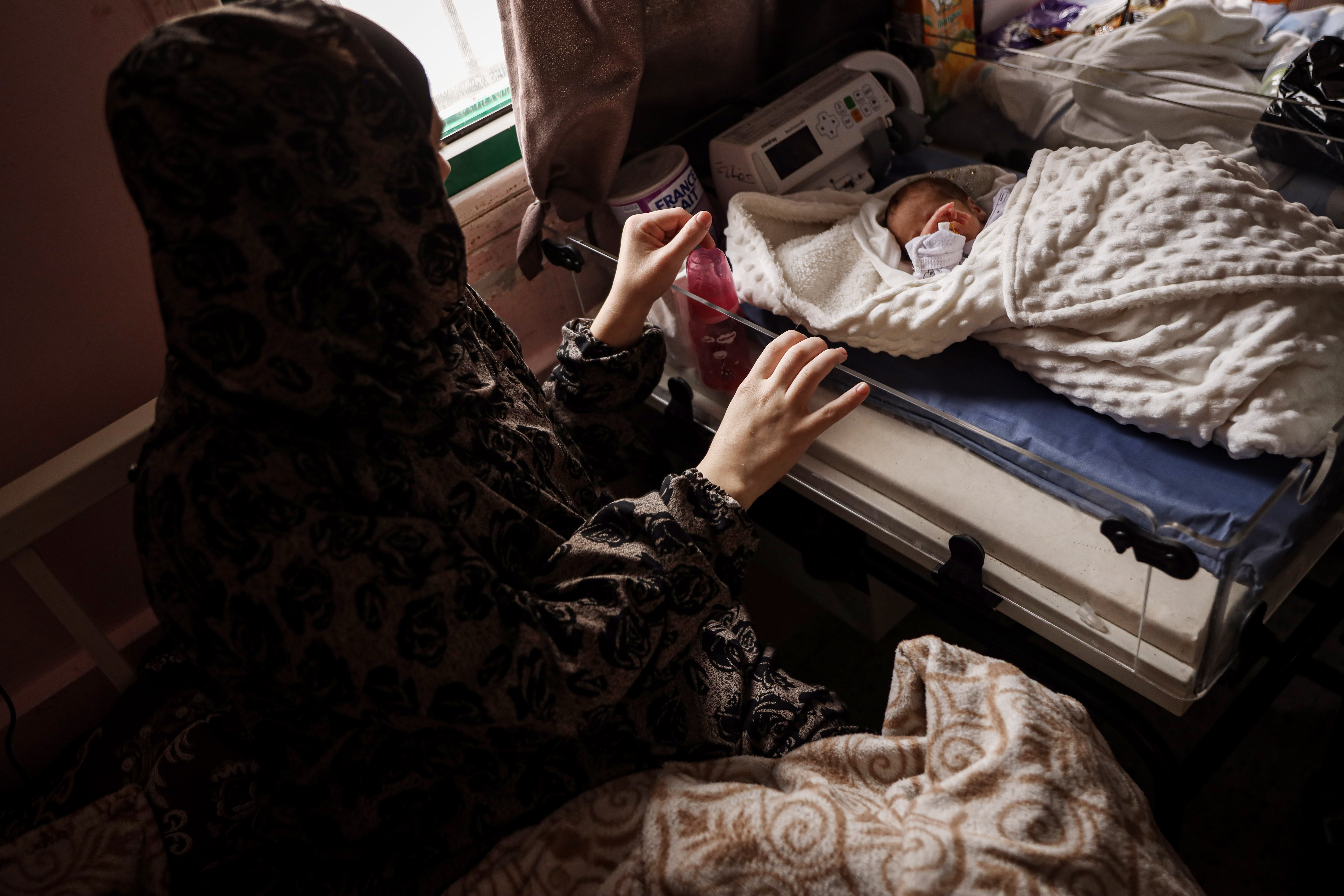 Rania Fadel stays with her premature son, Ilyas, in the external neonatal unit at Nasser Medical Complex in Khan Younis, practising kangaroo care to support his recovery. [Abdelhakim Abu Riash/ Al Jazeera]