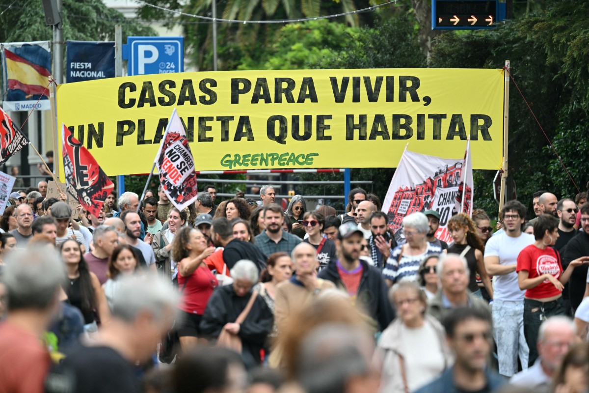 A demonstrator holds a banner reading 'Houses to live in, planet to inhabit' during a protest against evictions and high rent prices on plaza de Cibeles in Madrid on October 3, 2026. Protests over housing are take place across Spain, a day after parliament rejected two government measures to strengthen protection for tenants. (Photo by JAVIER SORIANO / AFP)