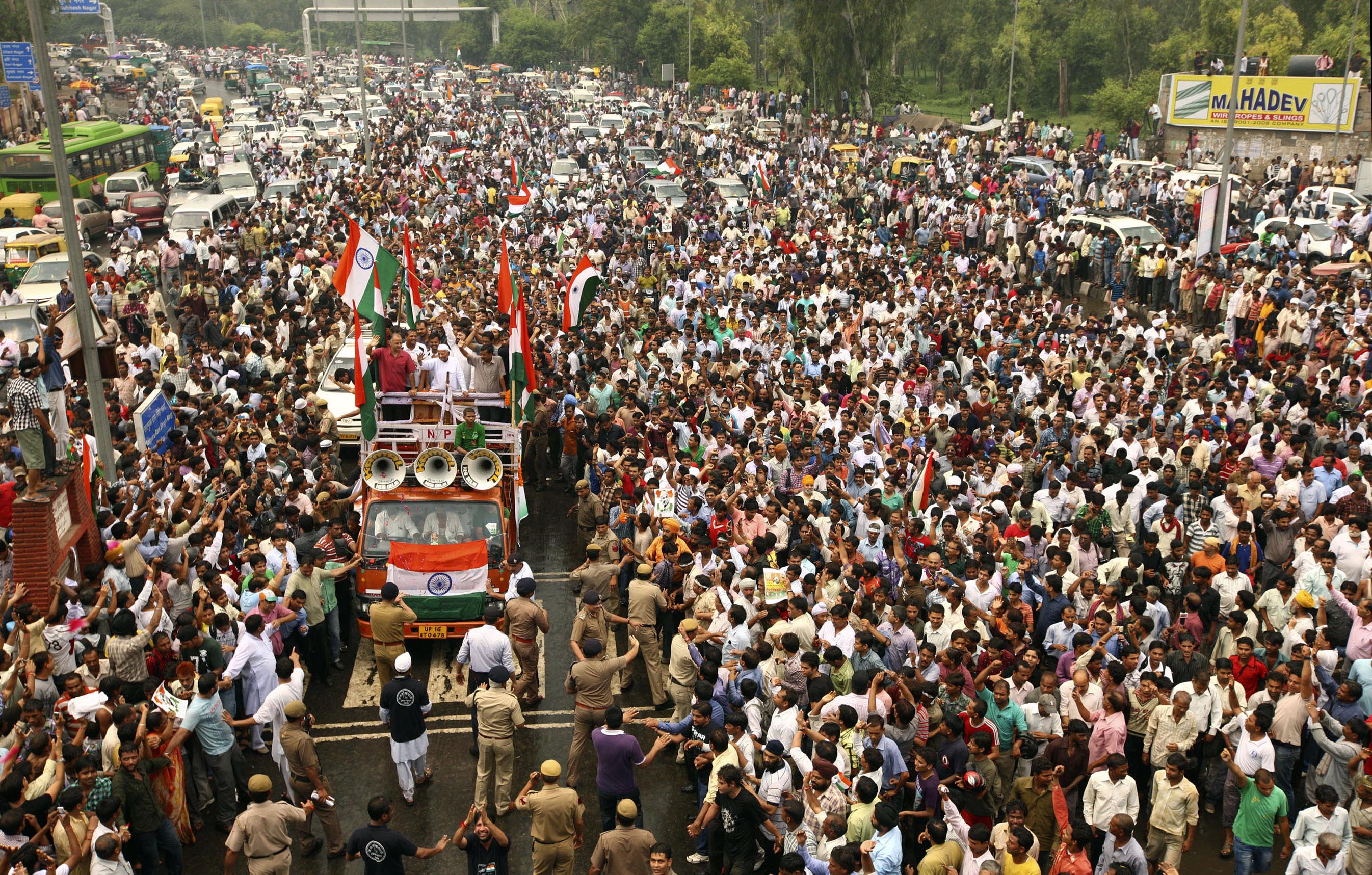 India’s most prominent anticorruption crusader Anna Hazare, wearing a white cap on a truck, waves to the crowd during a slow-moving procession to a protest venue, in New Delhi, August 19, 2011 [AP Photo]