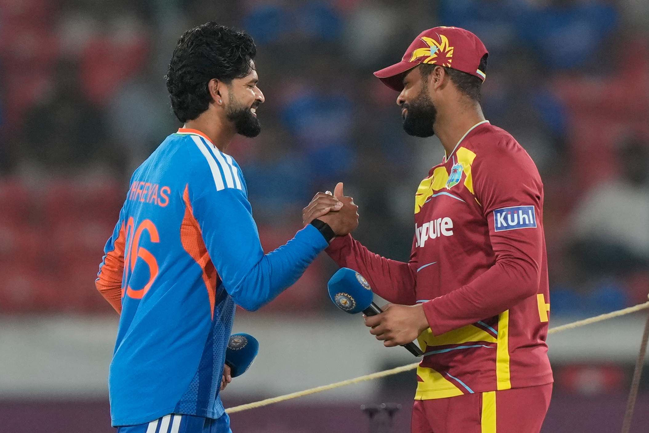 India's Shreyas Iyer, left, and West Indies' Shai Hope shake hands and smile.