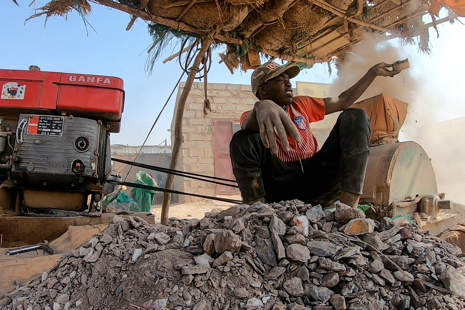 An artisanal miner breaking stones to extract gold, Dalago market [Mojahid Satti/Al Jazeera]