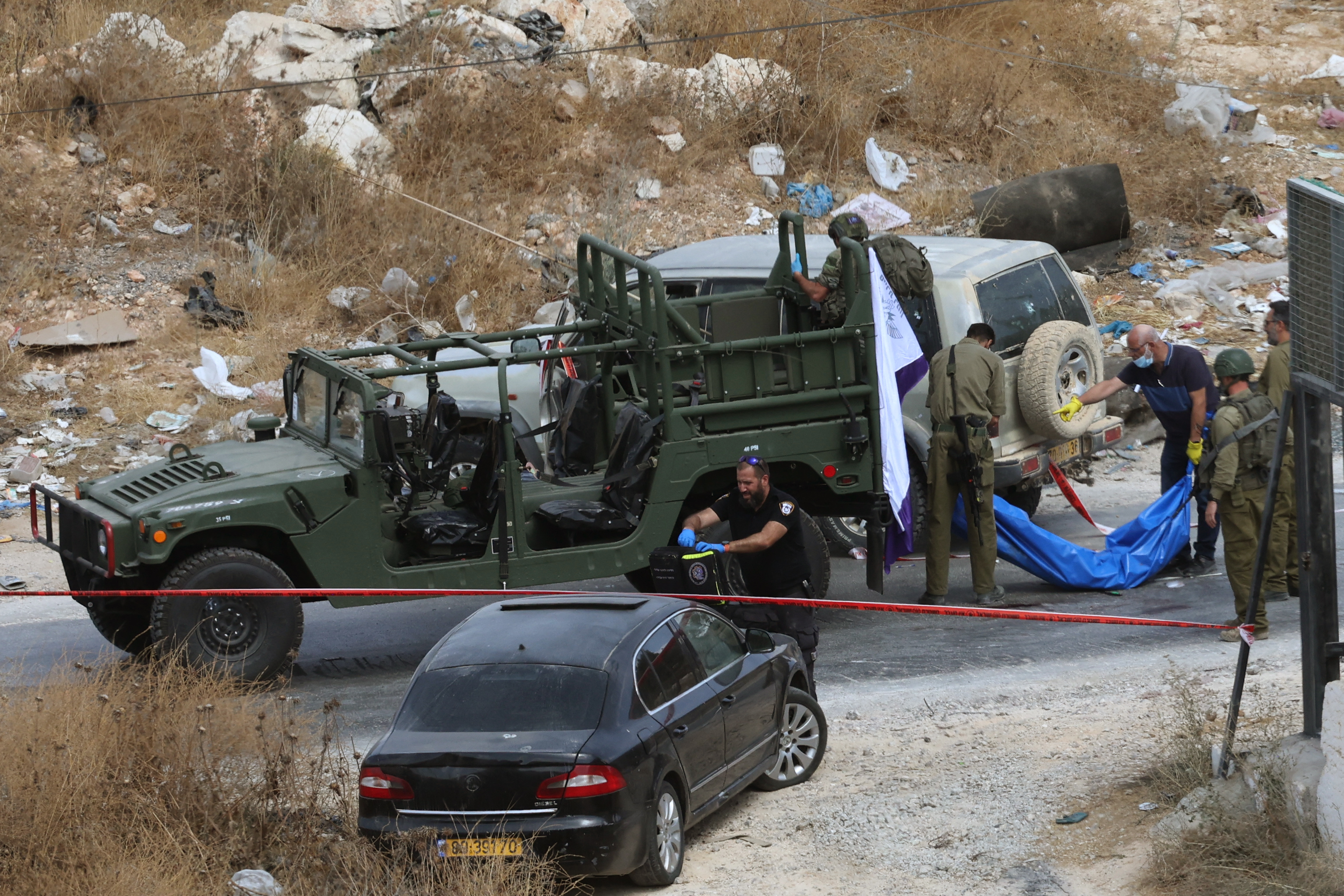 EDITORS NOTE: Graphic content / Israeli soldiers carry the body of a Palestinian man, shot by Israeli forces in an incident in which a car hit a military jeep near the Israeli-occupied West Bank town of Bani Naim on October 5, 2026. (Photo by Ahmad GHARABLI / AFP)