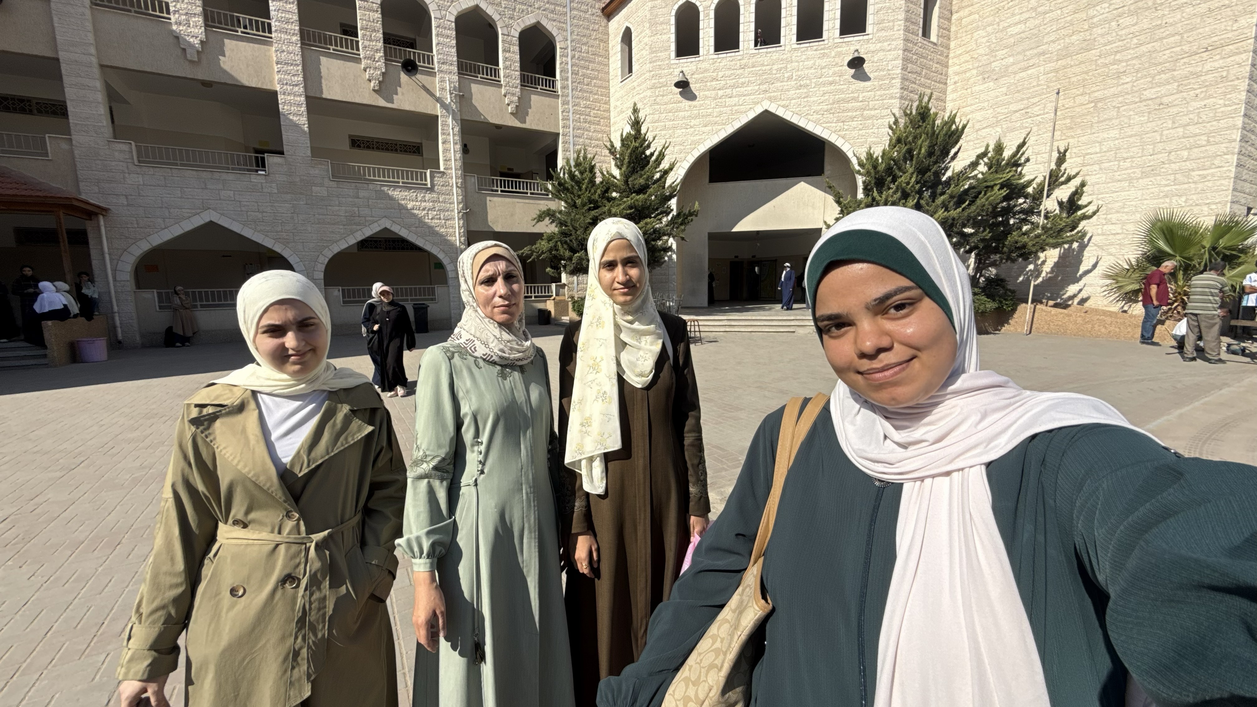 Aya Adnan [R] tries to recreate the schoolyard selfie with her friends Yasmin Abu Zaid [L], teacher Maha Taha, and Lina Yunis Abd al-Qader