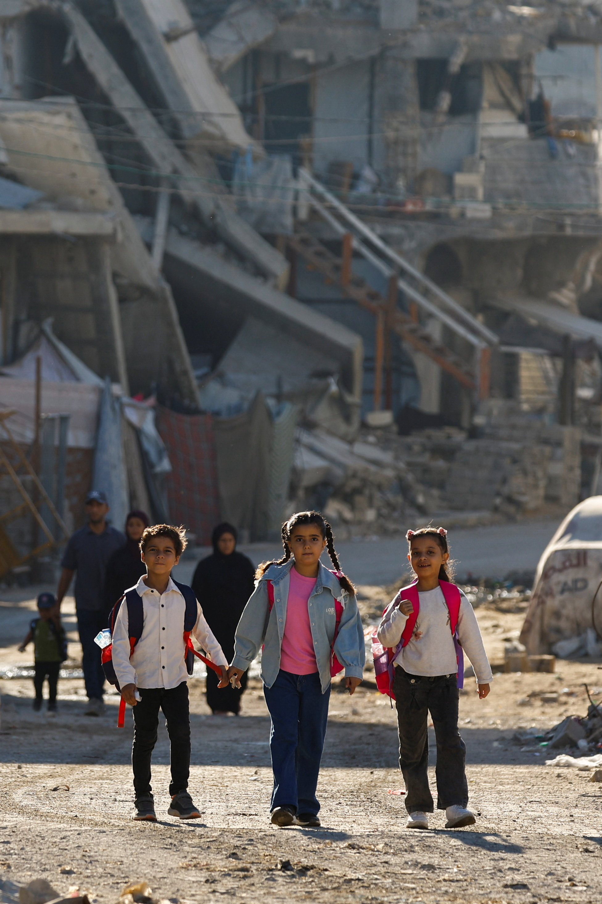 Palestinian children walk amid the rubble of buildings destroyed during the war, in Gaza City, October 7, 2026. REUTERS/Mahmoud Issa