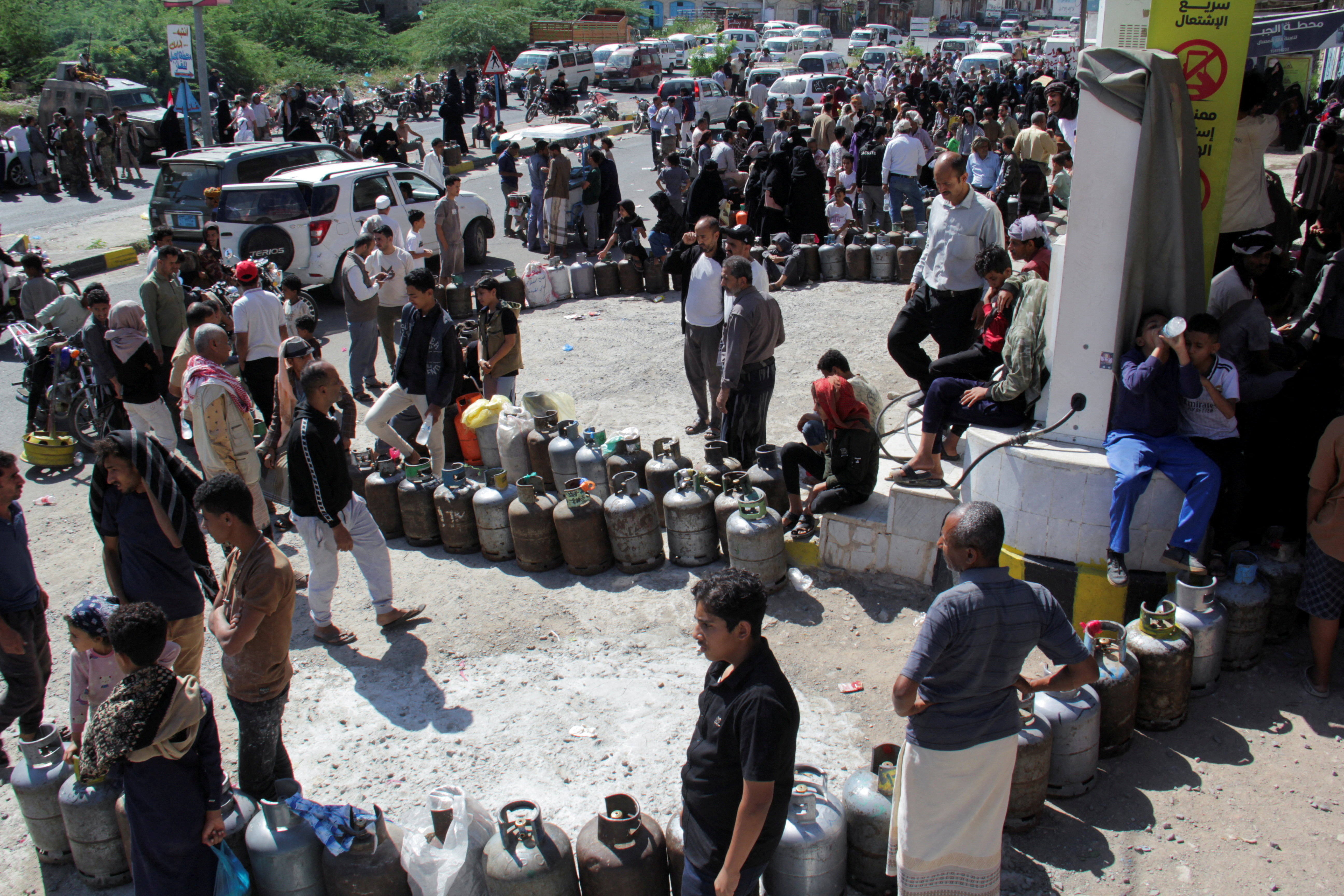 People wait outside a gas station to fill up cooking gas cylinders in the southwestern city of Taiz, Yemen