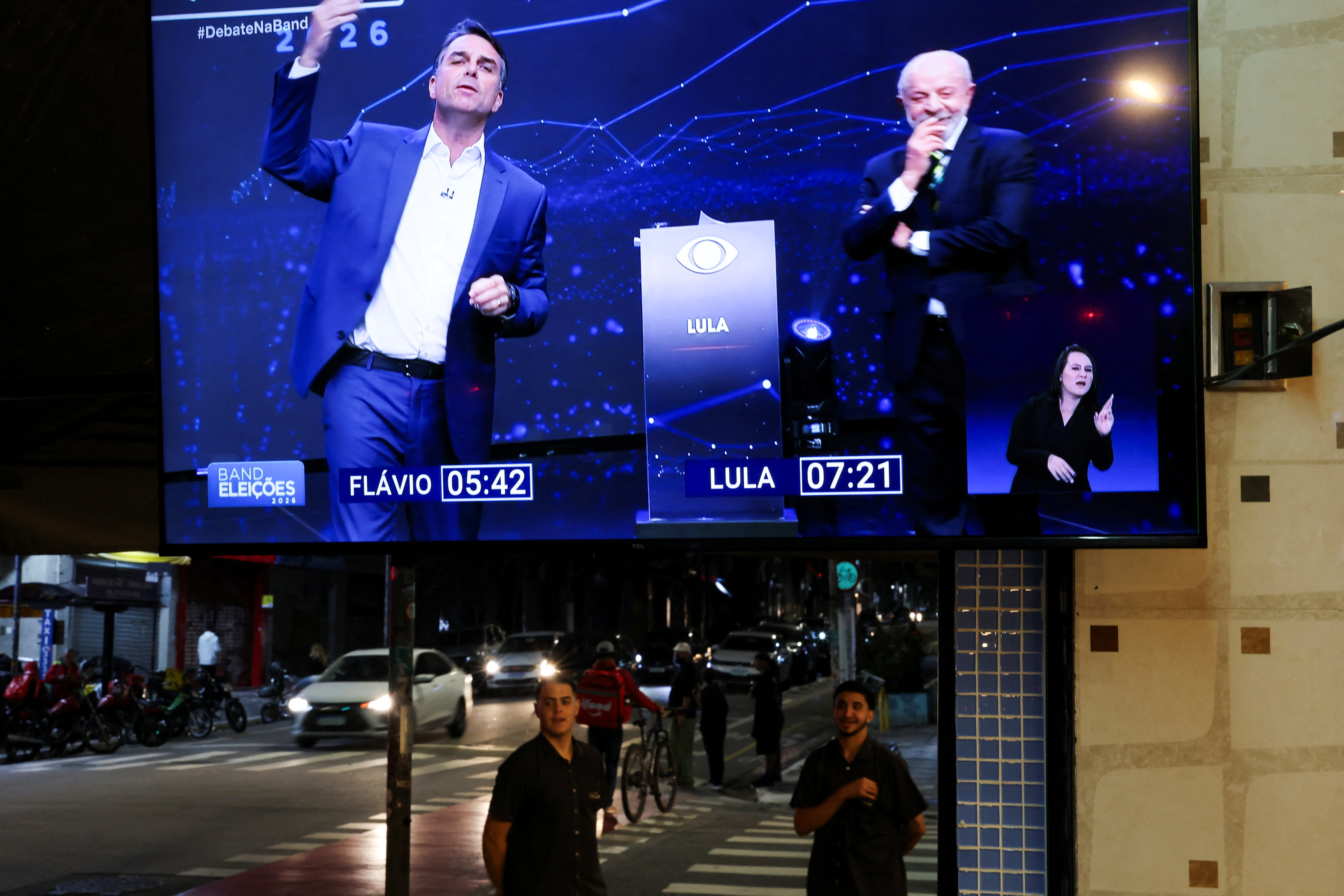 People stand as the presidential debate between Brazilian presidential candidate Flavio Bolsonaro of the Liberal Party (PL) and Brazilian President Luiz Inacio Lula da Silva of the Workers' Party (PT) is shown on TV, ahead of the runoff presidential election, in Sao Paulo , Brazil, October 18, 2026. REUTERS/Amanda Perobelli