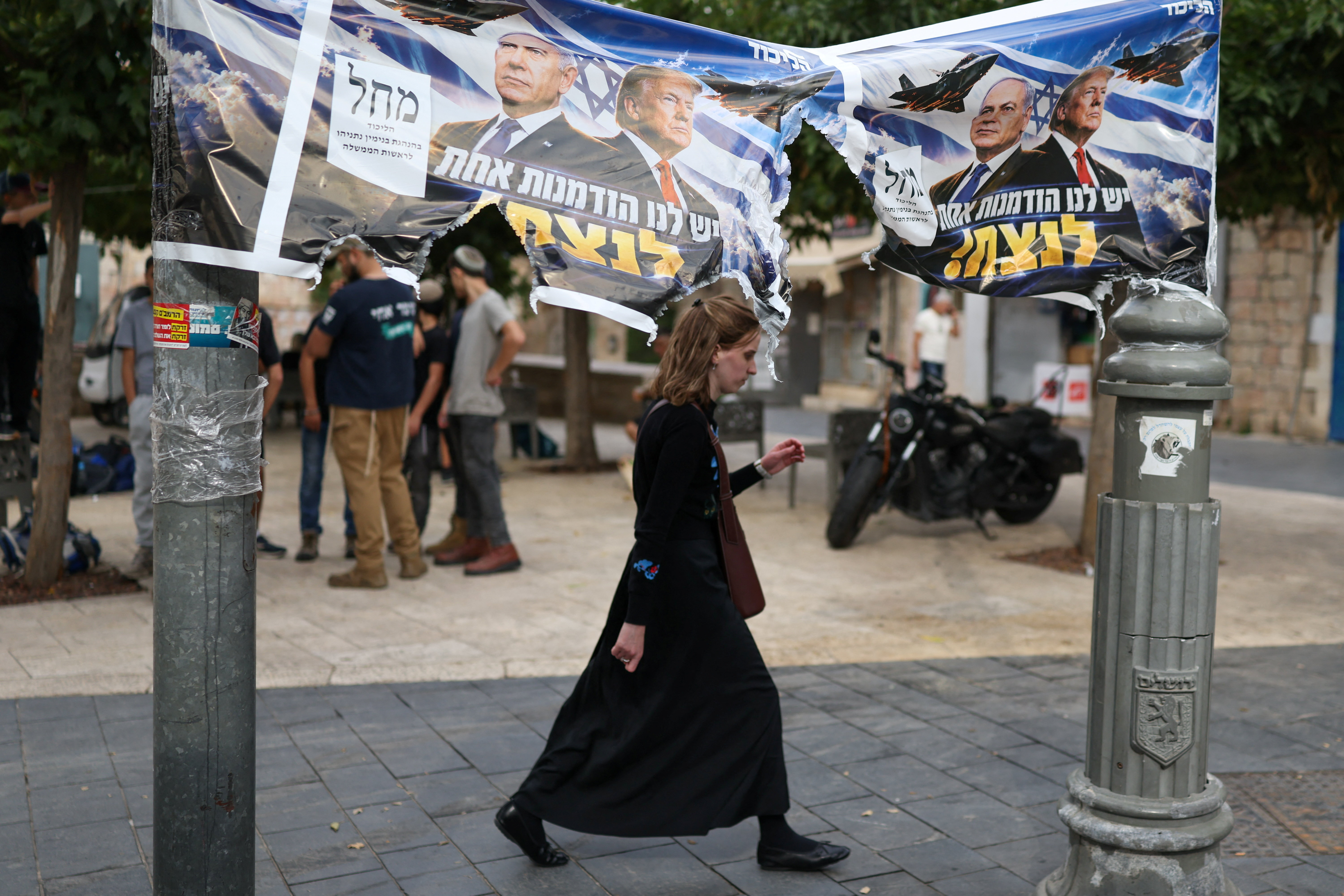 A woman passes by a banner depicting Israeli Prime Minister Benjamin Netanyahu and US President Donald Trump the day after the country's election